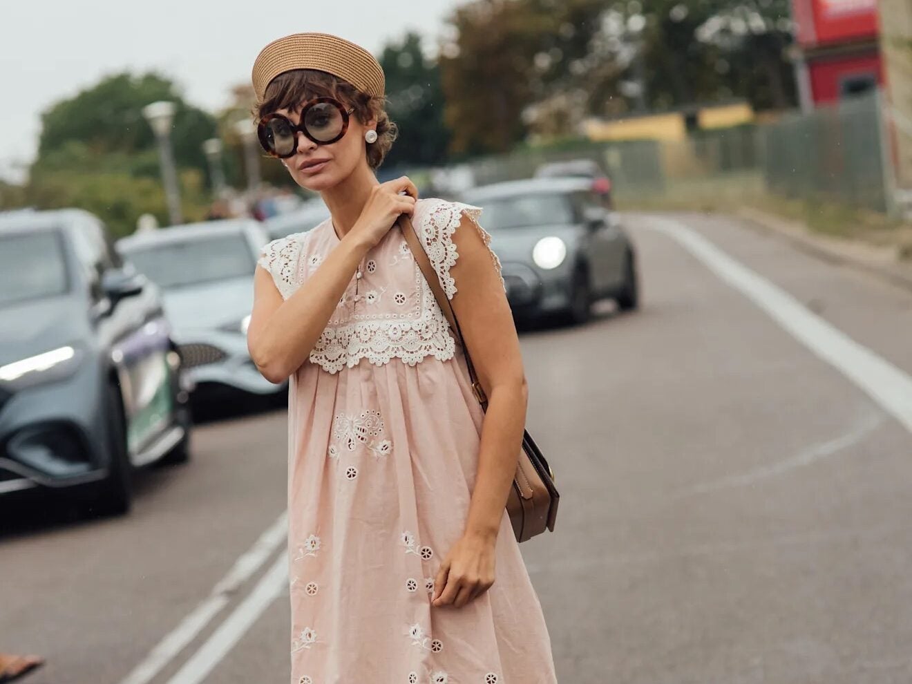 Mujer con vestido largo rosa claro con detalles de encaje blanco y boina en la calle.