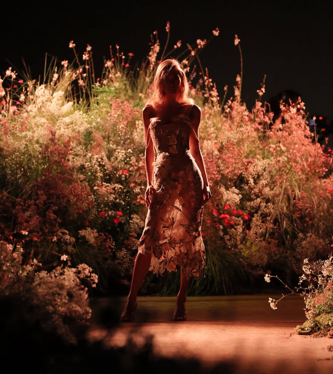 Modelo con vestido de flores y flores de fondo