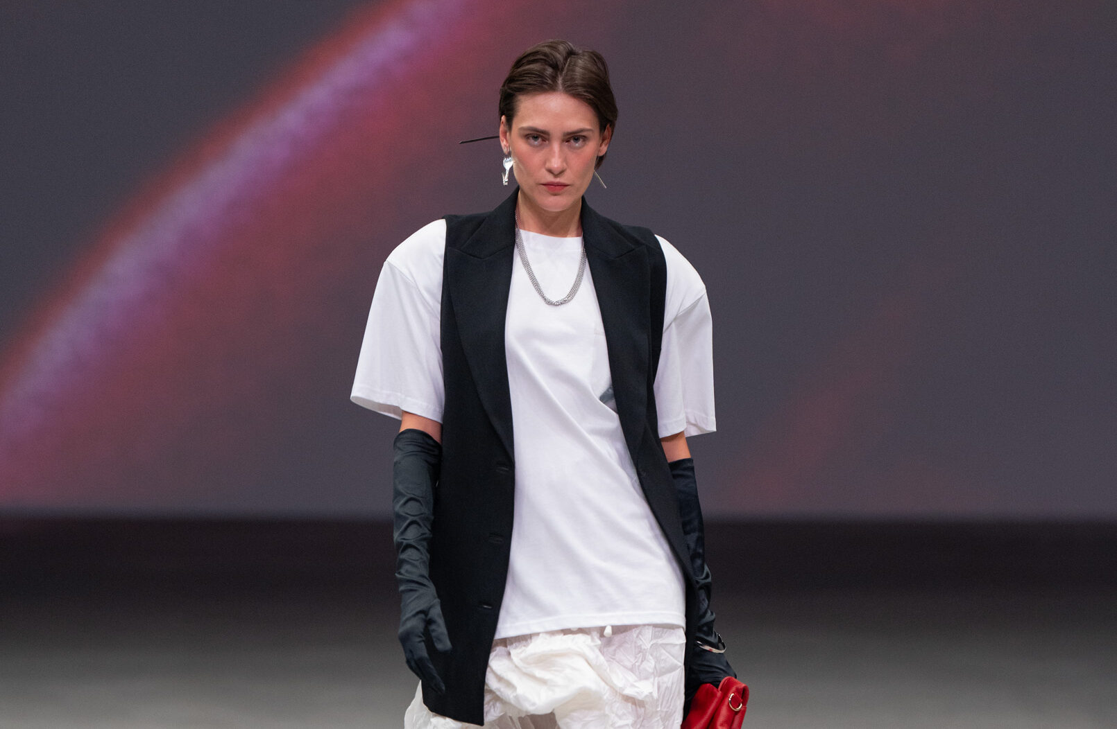 En el marco del Volvo Fashion Week México, Alejandra de Coss se posiciona como una fuerza innovadora al presentar su colección titulada Objetos Utilitarios. Esta propuesta redefine la moda contemporánea, invitando al espectador y al público a replantear la manera en que percibimos el vestir. Cucharas, llaves, peines y tenedores abandonan su función original para convertirse en elementos ornamentales cargados de significado, demostrando que la creatividad no tiene límites y que cada objeto puede transformarse en un vehículo de expresión personal. La colección no solo impacta por sus accesorios, sino por cómo cada prenda cuestiona los códigos tradicionales de la moda. Faldas que se convierten en tops, vestidos que se dividen y blazers que se fragmentan, muestran un enfoque experimental que invita a pensar en la vestimenta como un acto consciente y flexible. La arquitectura de las piezas se percibe en siluetas estructurales y atemporales que, a pesar de su innovación, mantienen un equilibrio entre funcionalidad y estética. La paleta de colores refleja la dualidad de lo cotidiano y lo extraordinario. Blancos, crudos y negros se combinan con rojos intensos y delicados toques de café chocolate, generando una armonía visual que resalta la elegancia inherente de cada diseño. Esta selección cromática no solo aporta sofisticación, sino que también sirve para enfatizar la intención conceptual detrás de cada prenda, donde cada línea, pliegue y volumen tiene un propósito narrativo. Además, Alejandra de Coss logra que la interacción con la moda sea casi lúdica. Los accesorios convertidos de objetos cotidianos permiten que el público imagine nuevas formas de portar y personalizar su estilo. La propuesta de Objetos Utilitarios desafía la pasarela tradicional y establece un diálogo entre arte, moda y vida diaria, haciendo que cada pieza funcione como un espejo de identidad, historia y cultura contemporánea. En definitiva, esta colección marca un hito dentro del panorama de la moda mexicana. Alejandra de Coss demuestra que la innovación no está en la extravagancia, sino en la capacidad de reinventar lo ordinario y de invitar al usuario a una reflexión sobre el vestir consciente y creativo. Objetos Utilitarios es más que una colección, es una invitación a cuestionar, explorar y redefinir nuestra relación con la moda.