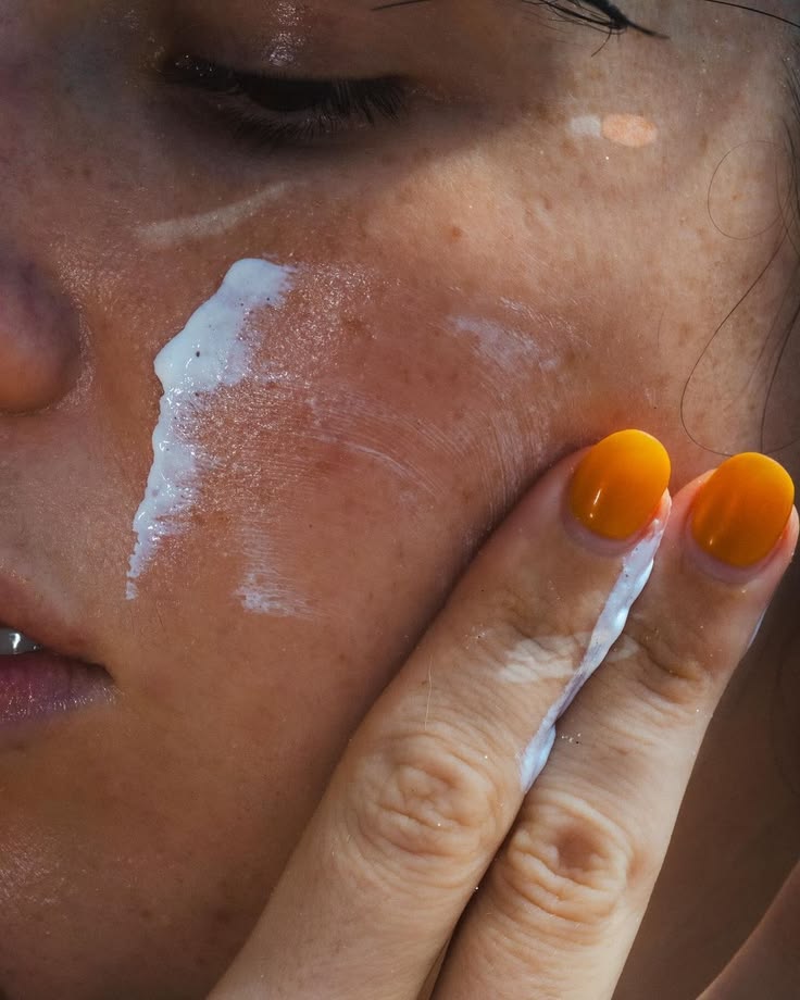 Mujer extendiendo crema solar sobre rostro con pecas