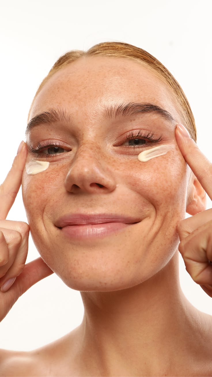 Mujer extendiendo crema hidratante sobre rostro con pecas