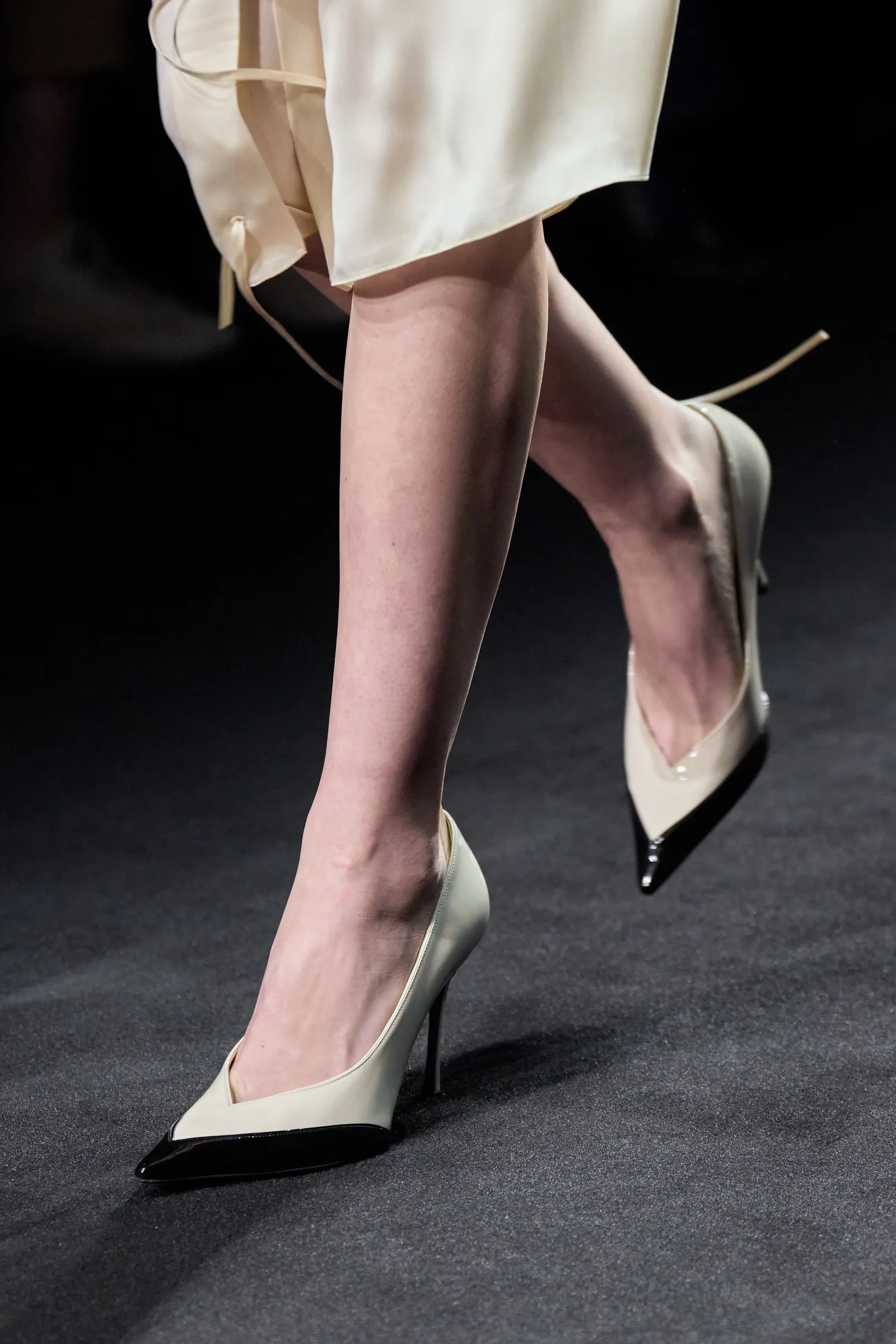 Zapatos de tacón en color marfil con punta negra en la pasarela.