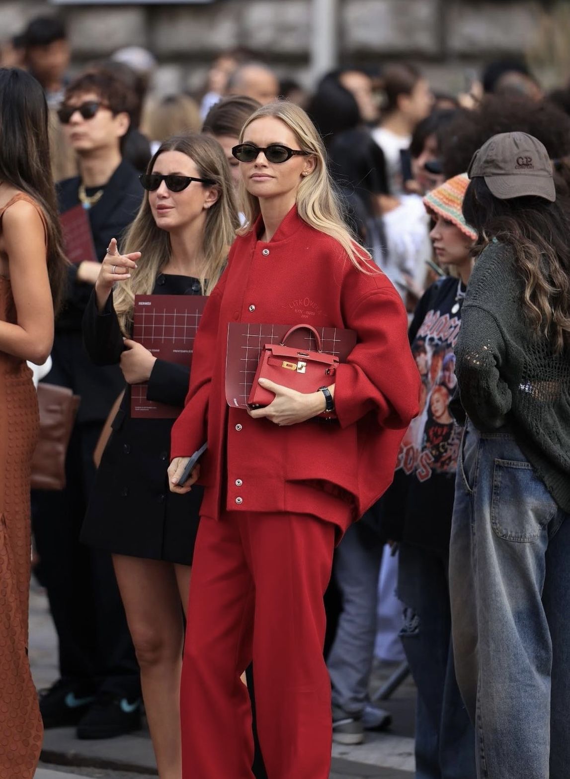 Mujer con chaqueta roja estilo bomber de lana, pantalones a juego y un pequeño bolso rojo tipo Kelly