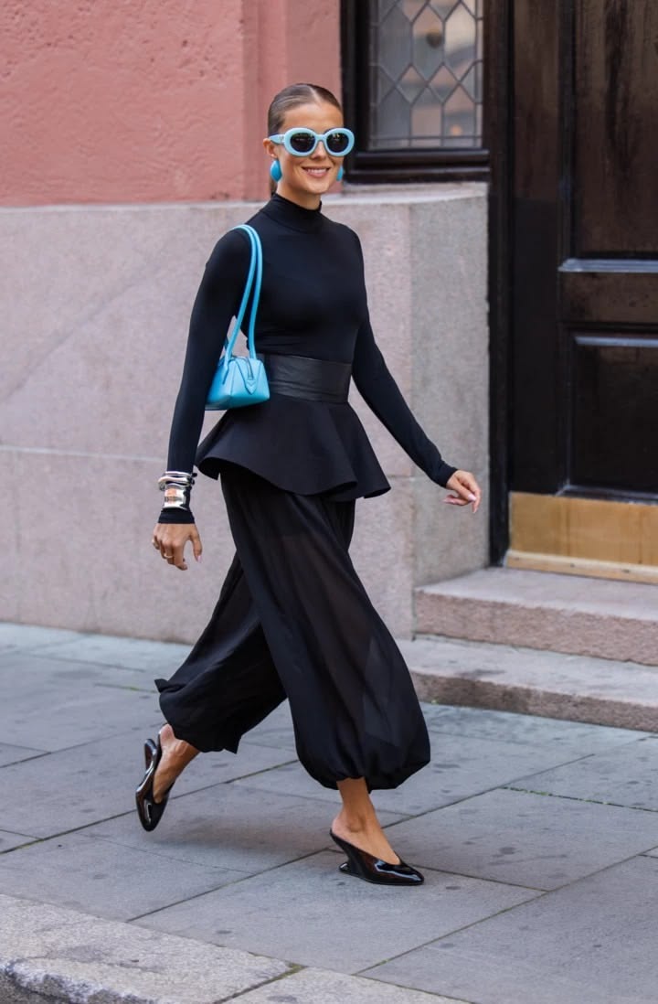 Mujer con conjunto negro, pantalón globo y lentes azules