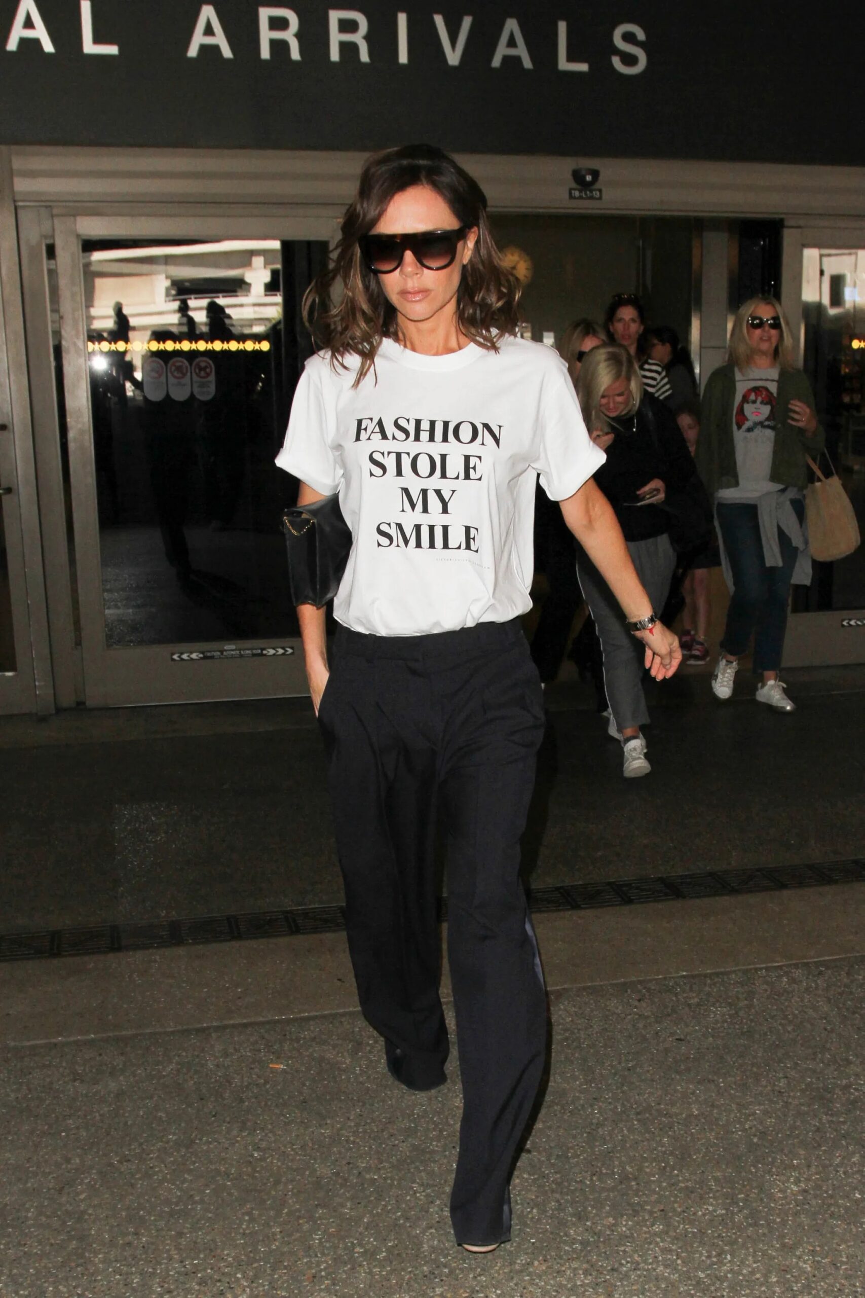 Victoria Beckham con camiseta gráfica saliendo de aeropuerto.