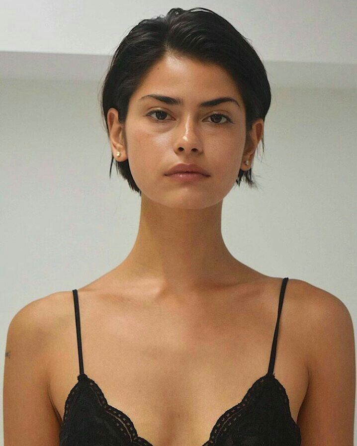 Mujer de cabello oscuro corto con un corte boy bob estructurado y limpio, usando un top de tirantes negro