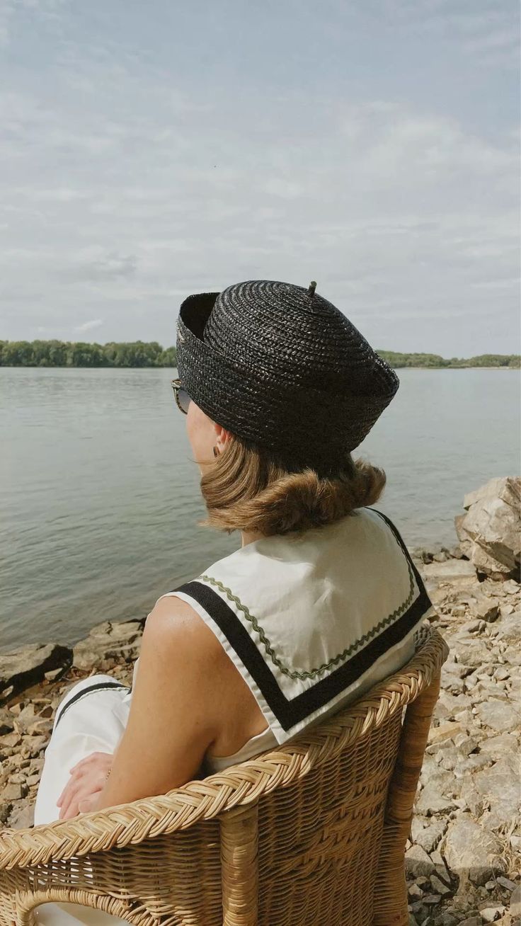 Mujer con sombrero negro frente al mar
