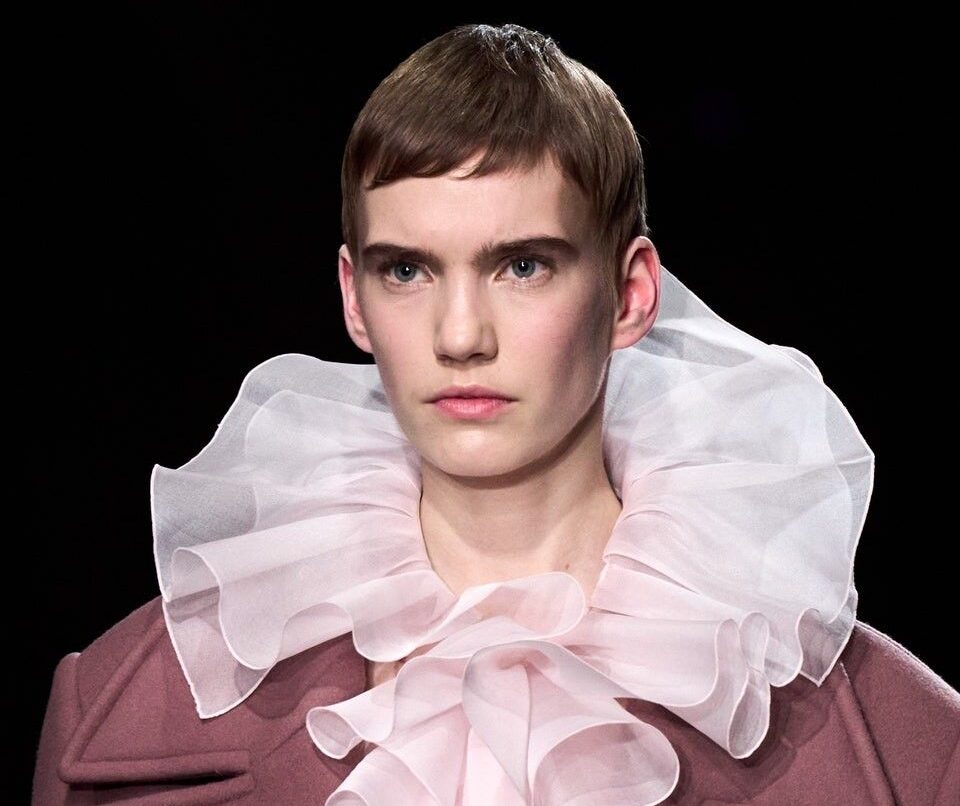 Modelo con maxi cuello plisado rosa y abrigo.