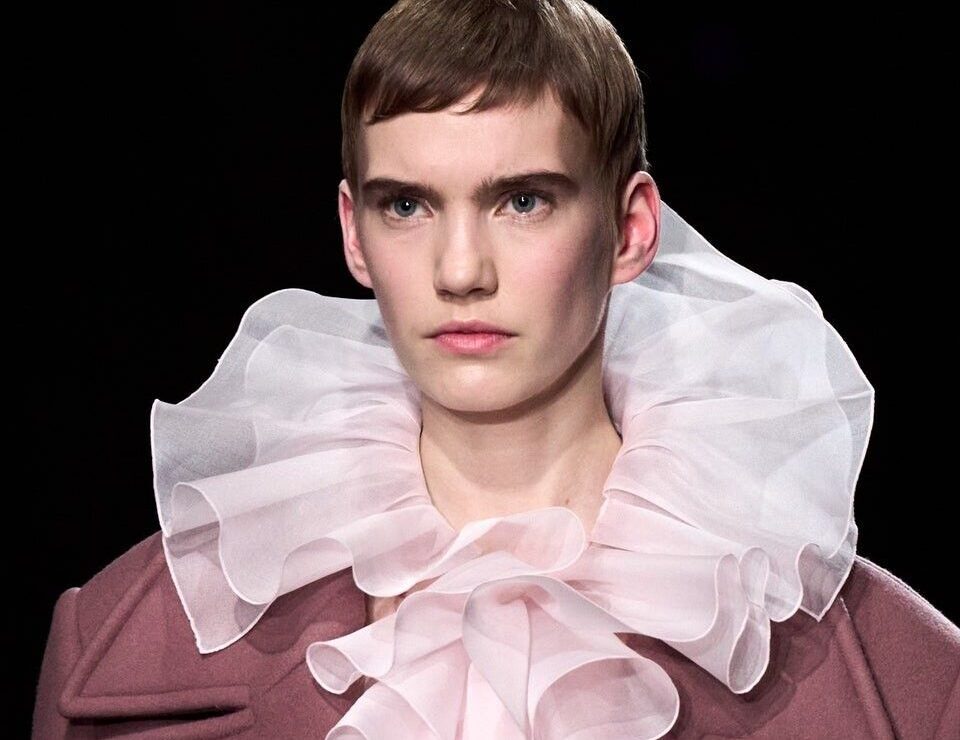 Modelo con maxi cuello plisado rosa y abrigo.