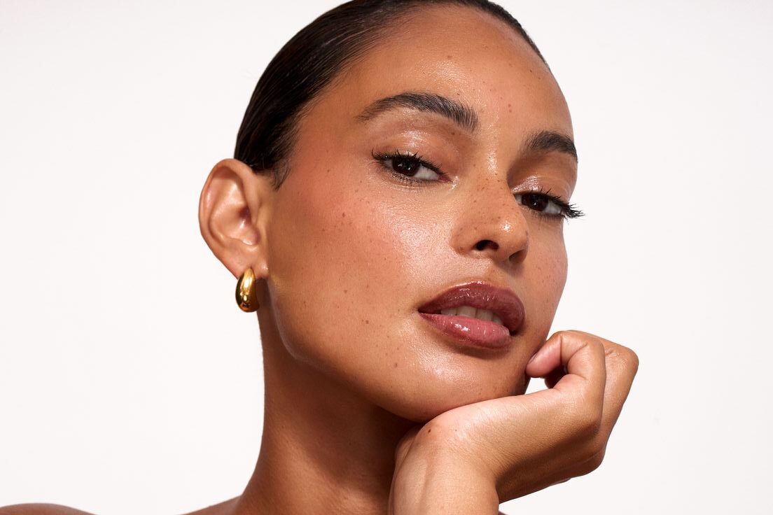 Primer plano de una modelo con piel luminosa, efecto mojado ("wet look") y labios con brillo natural