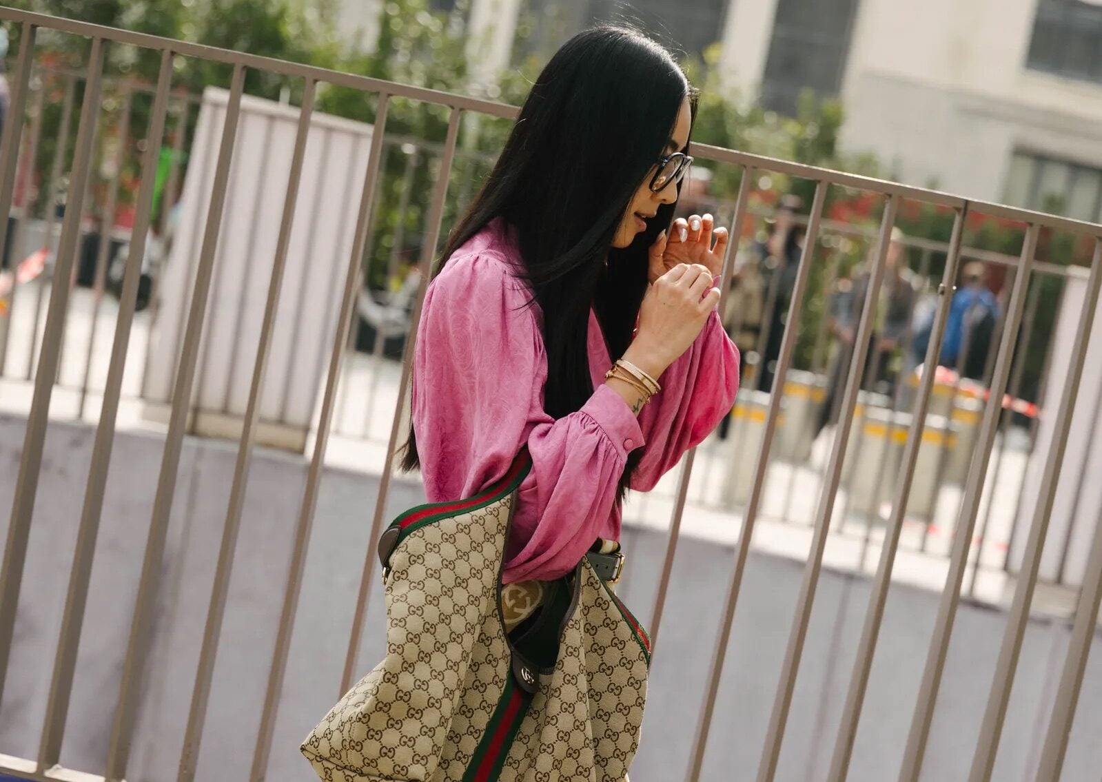 Mujer con blusa rosa y bolso Gucci Giglio caminando.