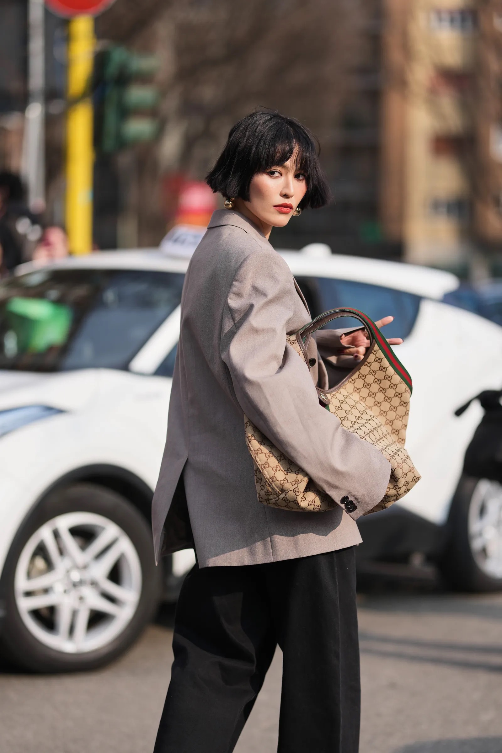 Mujer de cabello corto con blazer y bolso Gucci Giglio.