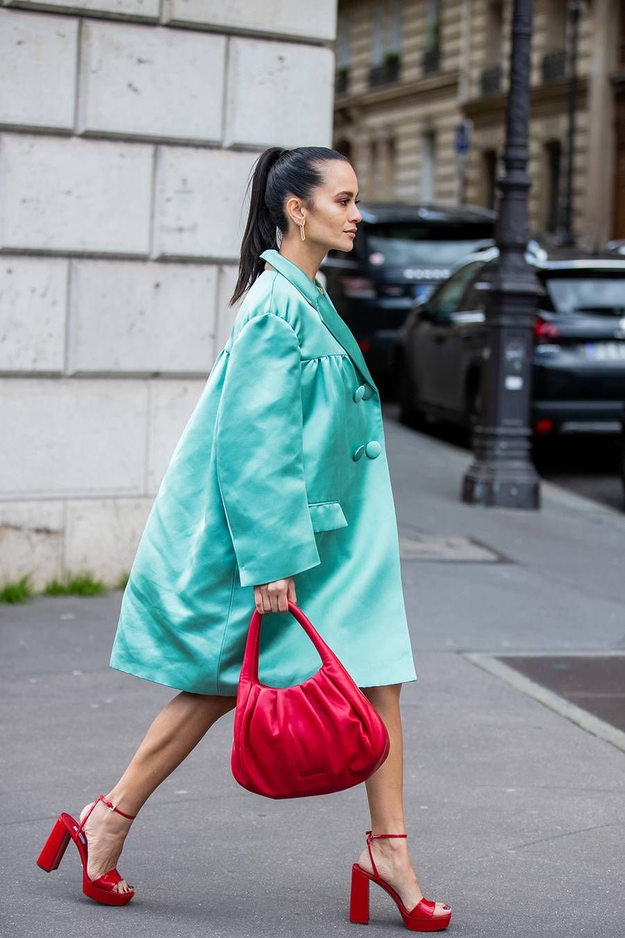 mujer vestida con abrigo color turquesa con zapatos y bolso rojos