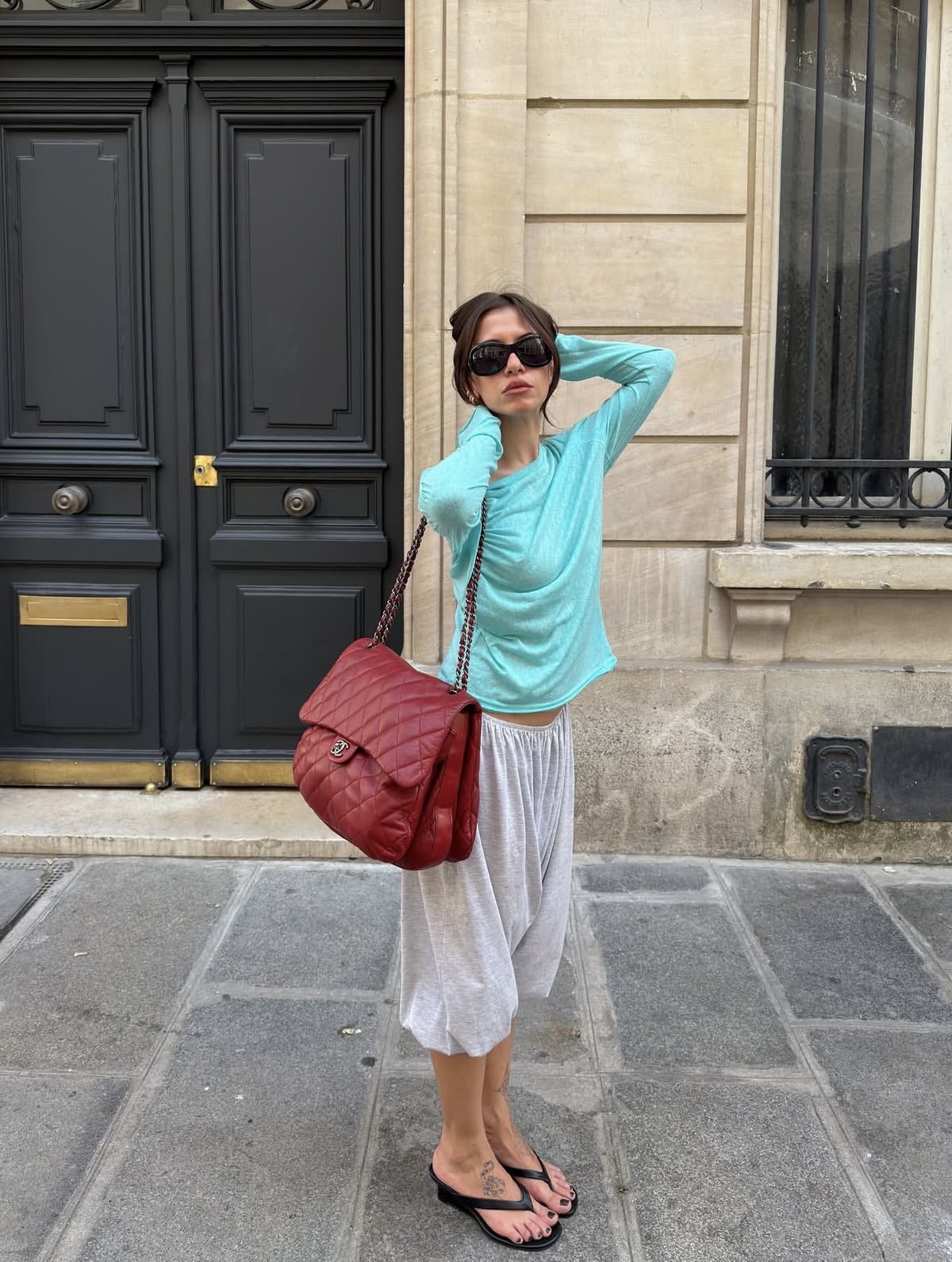 Mujer vestida con blusa turquesa y bolso rojo