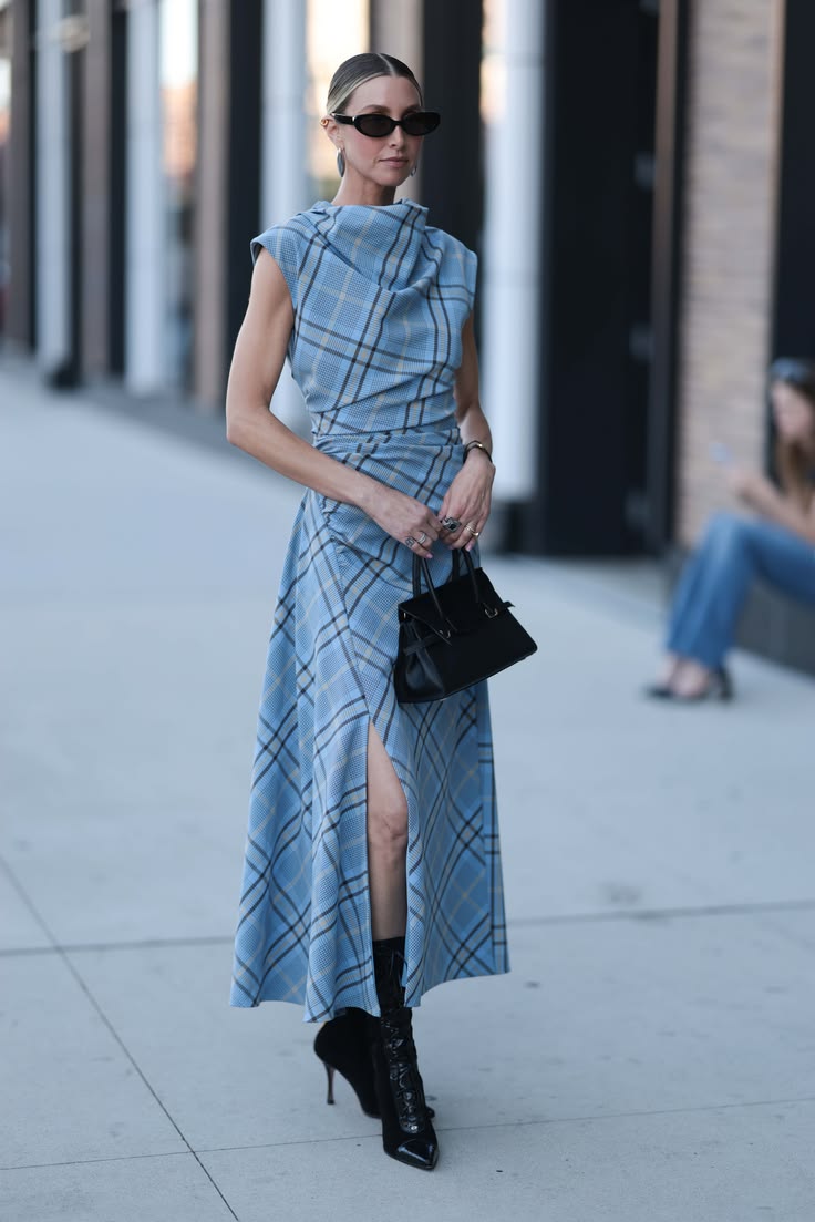 Mujer con vestido midi de cuadros en tonos azules, cuello drapeado, abertura lateral y botines negros de tacón