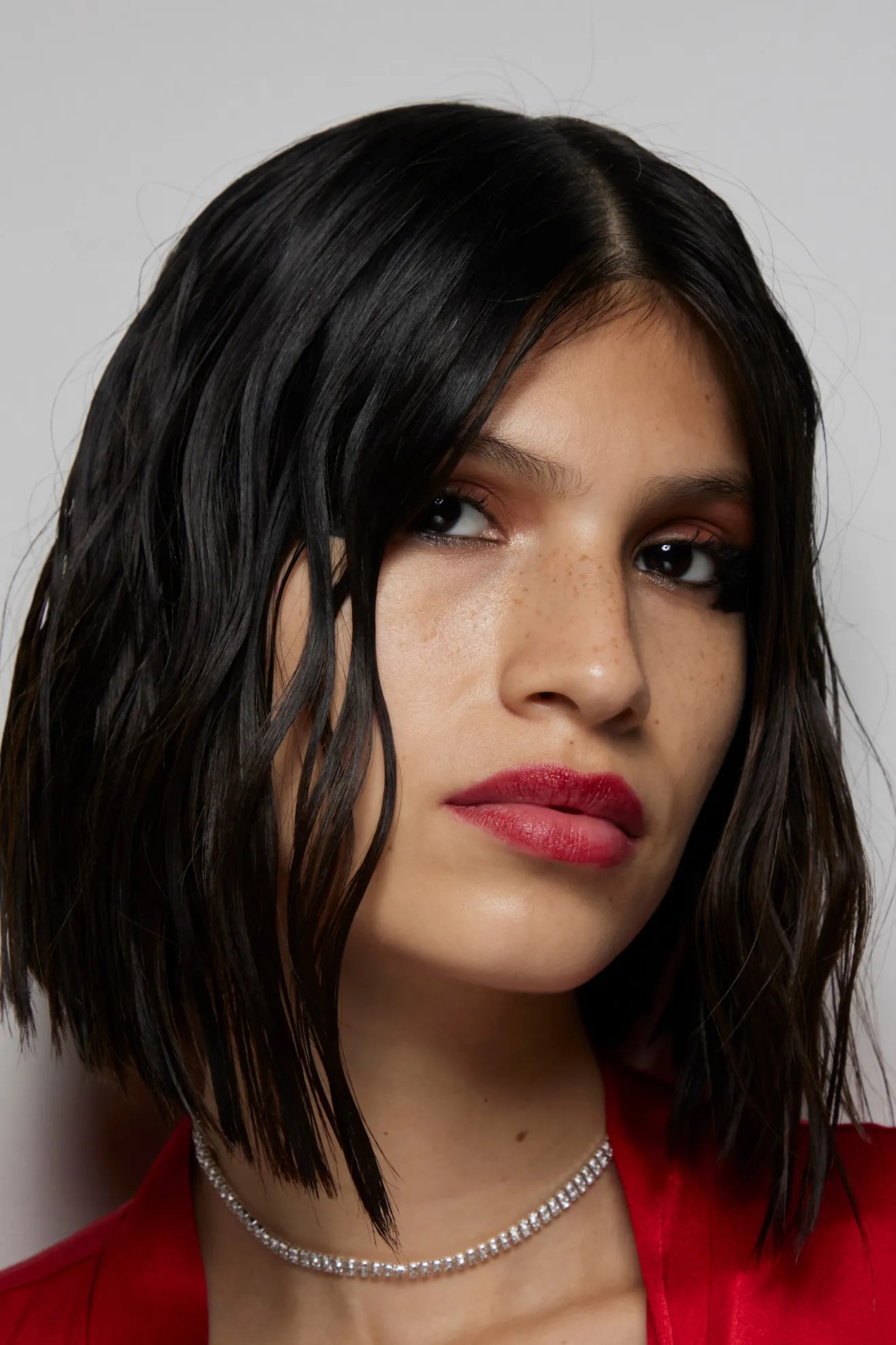 Rostro de modelo con cabello oscuro, brillante y efecto pulido estilo glass hair.