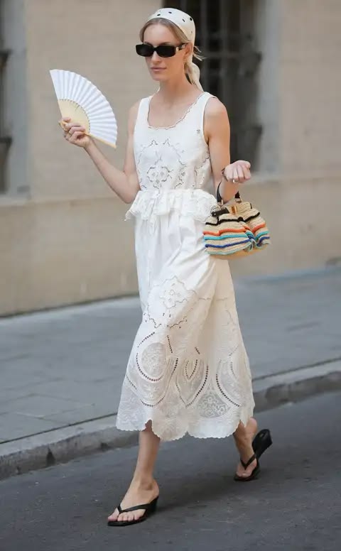 Mujer con vestido blanco bordado, pañuelo en la cabeza y abanico