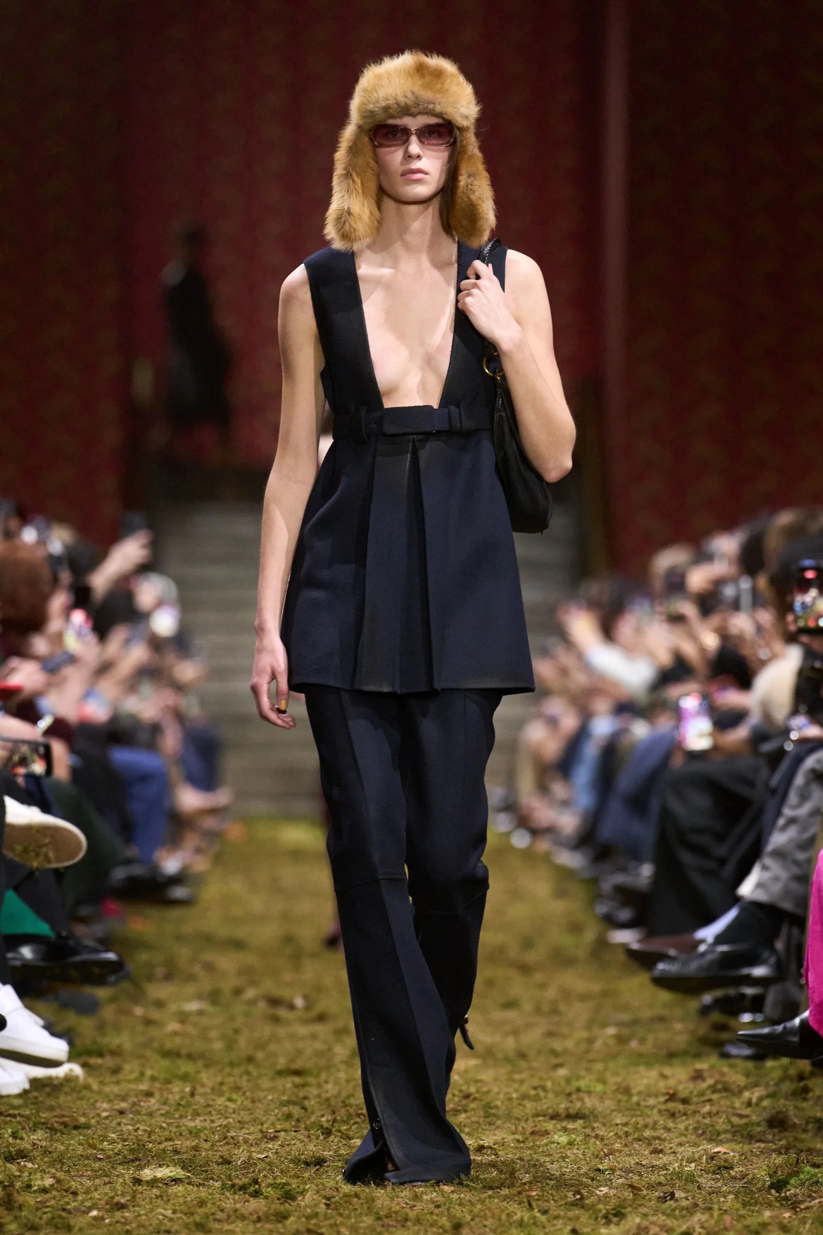 Modelo con gorro de piel, top sin mangas y pantalón negro largo en la pasarela.