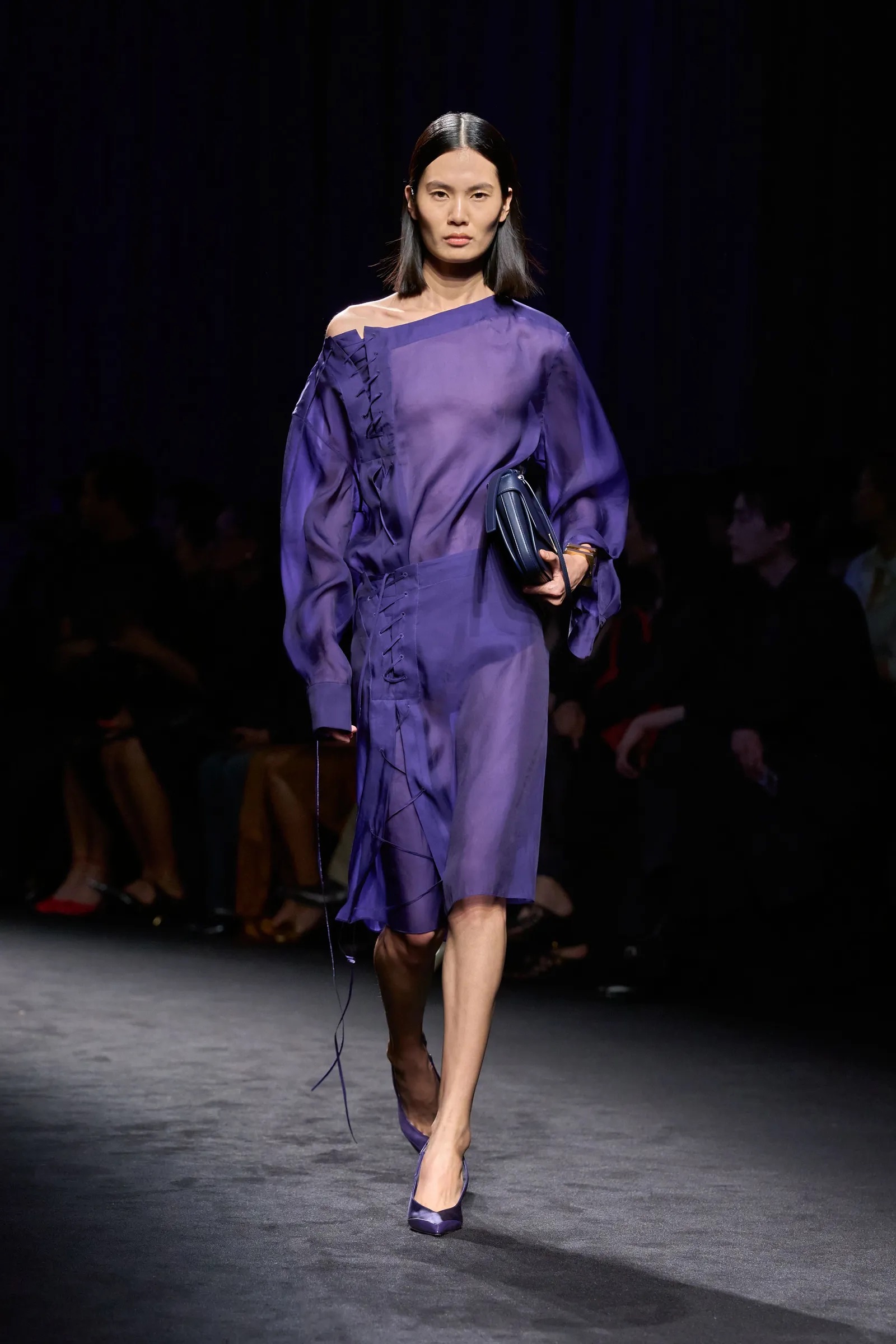 Modelo de cabello negro con vestido semitransparente morado amatista con cordones.