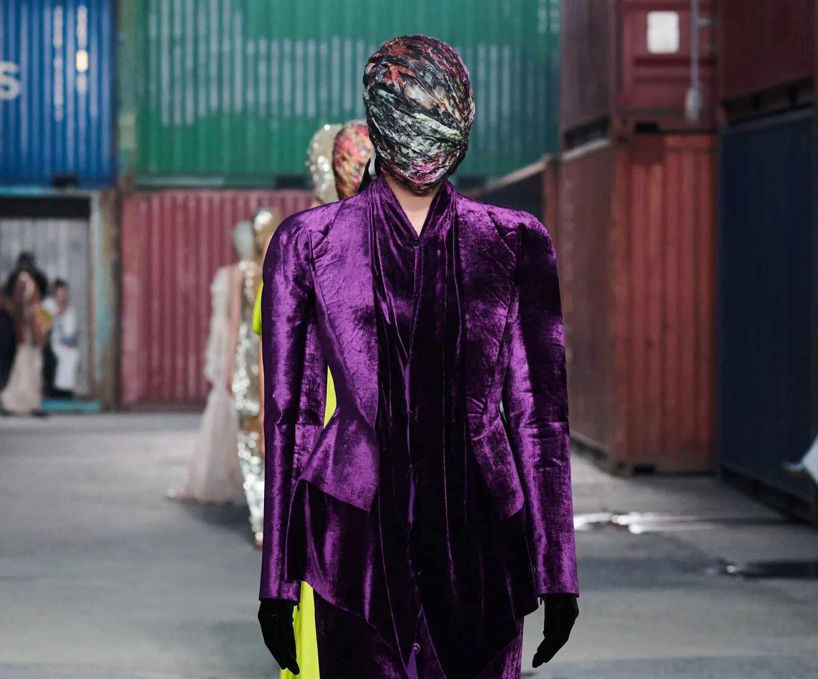 Modelo con conjunto de terciopelo morado amatista y tocado estampado en exteriores industriales.