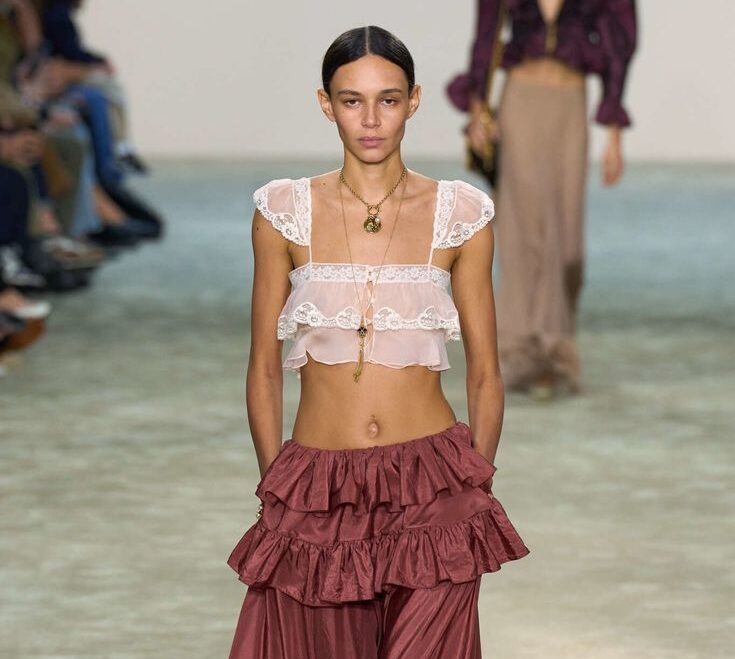 Modelo con top corto rosa de encaje y falda larga borgoña con volantes en pasarela.