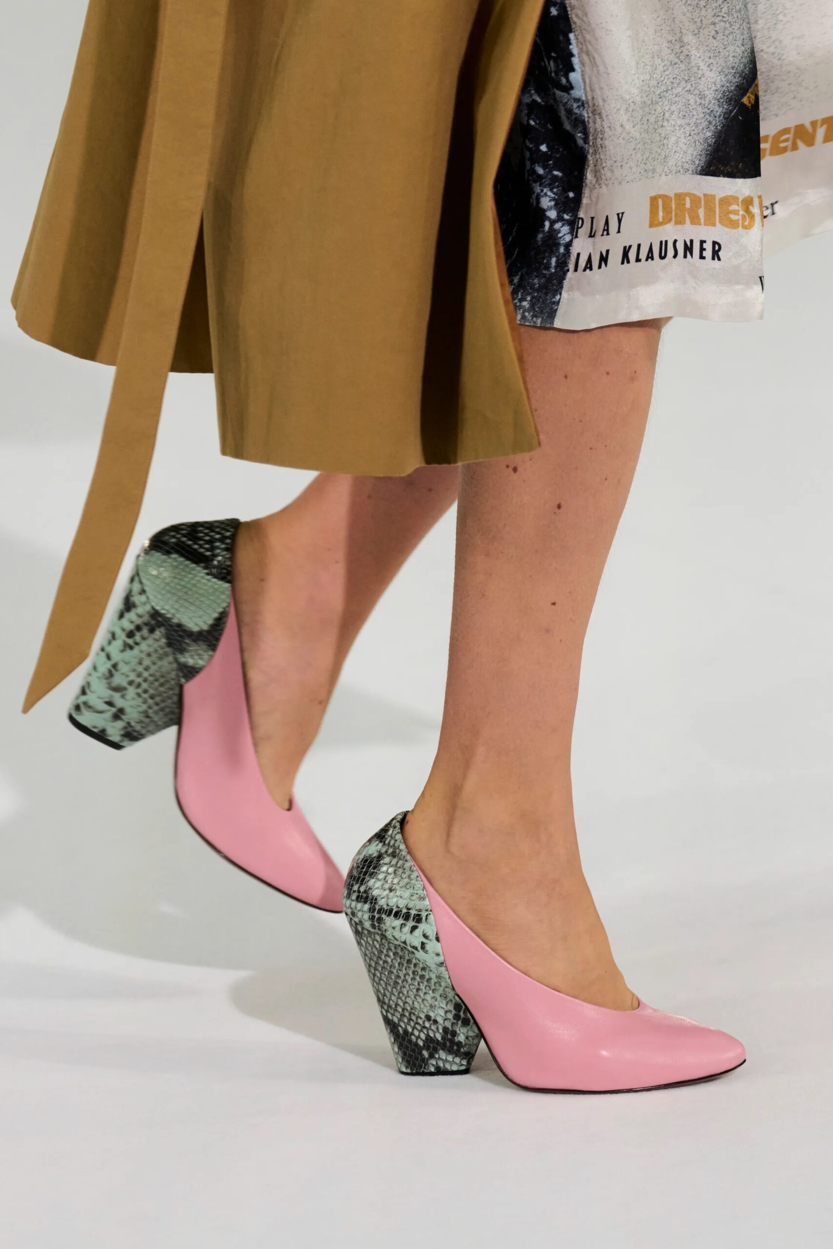 Detalle de los zapatos de tacón ancho en color rosa pastel con inserciones de estampado tipo piel de serpiente en tonos verdosos.