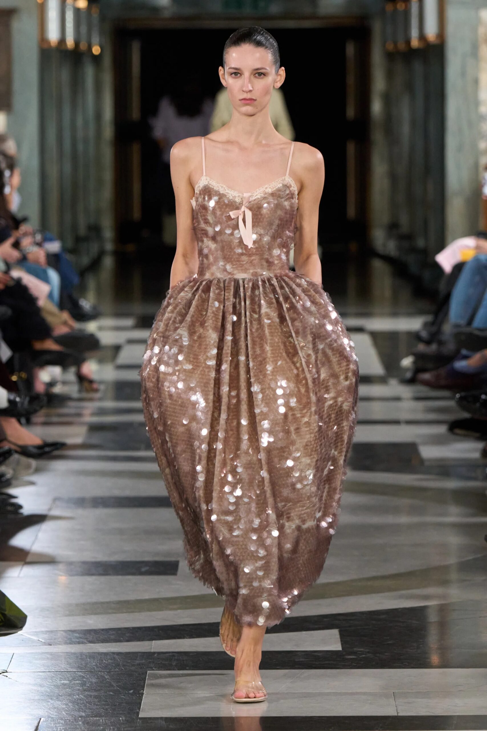 Modelo luciendo un vestido midi con tirantes finos en tono marrón brillante, cubierto de aplicaciones texturizadas y silueta abullonada