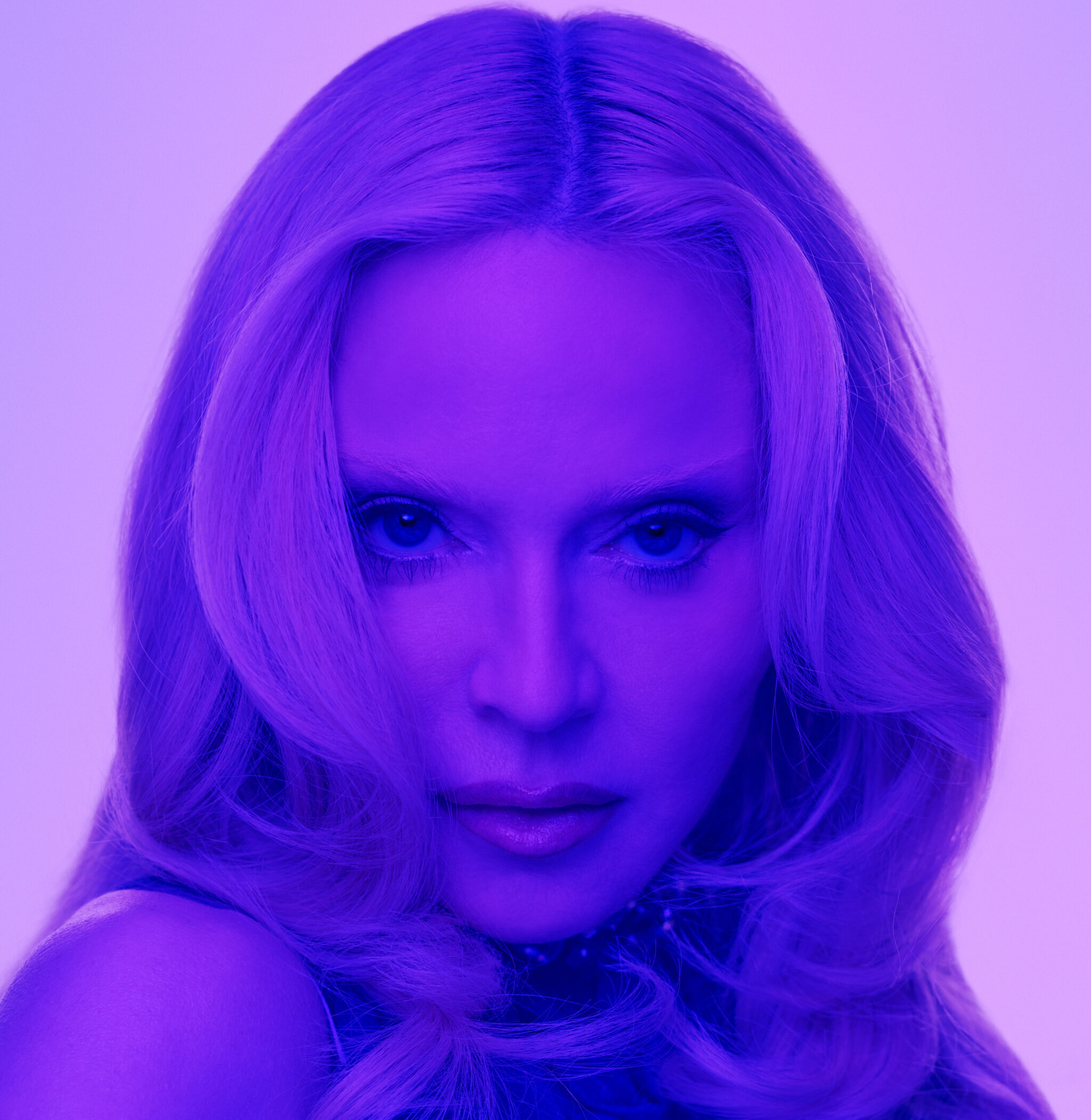 Primer plano de Madonna con iluminación y matices predominantemente en tonos violetas y azules, destacando su mirada y el logotipo blanco de KIKO Milano en la parte inferior.