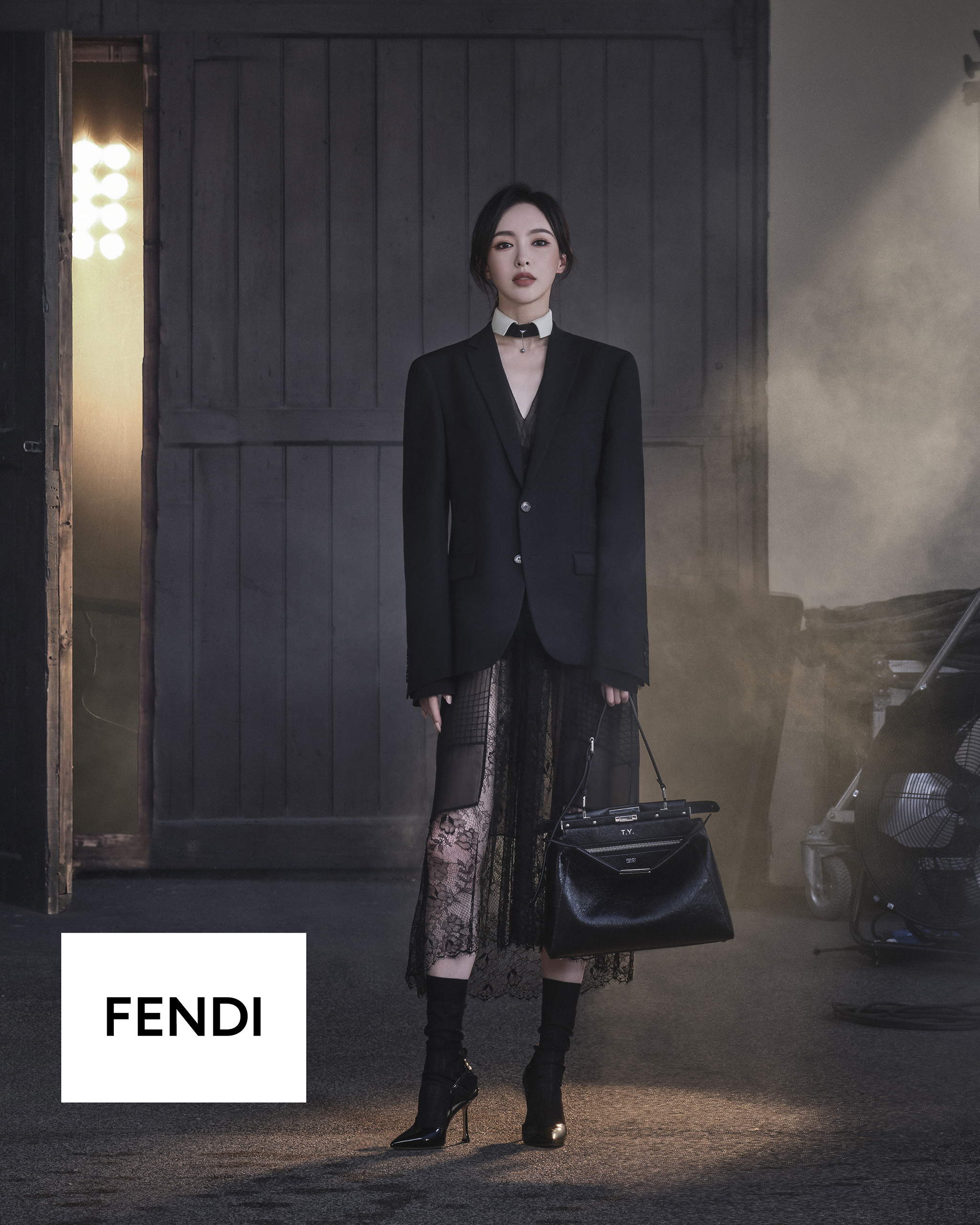 Tang Yan en el set de una sesión fotográfica de FENDI, vistiendo una americana estructurada sobre una falda midi transparente y oscura, con el bolso Peekaboo en la mano.