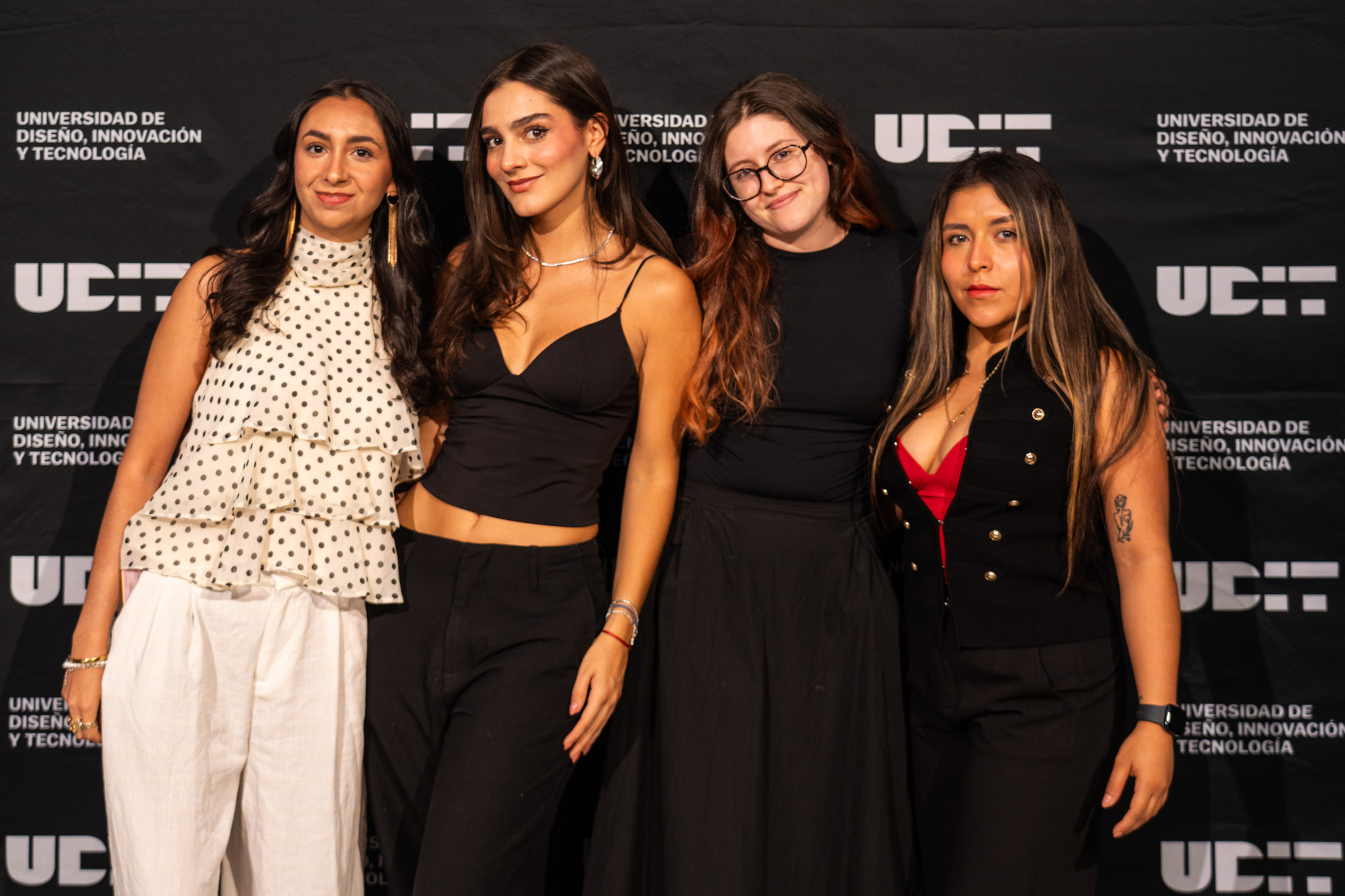 Fotografía grupal de cuatro jóvenes diseñadoras mexicanas posando sonrientes frente a un fondo negro con el logotipo de la Universidad de Diseño, Innovación y Tecnología (UDIT).