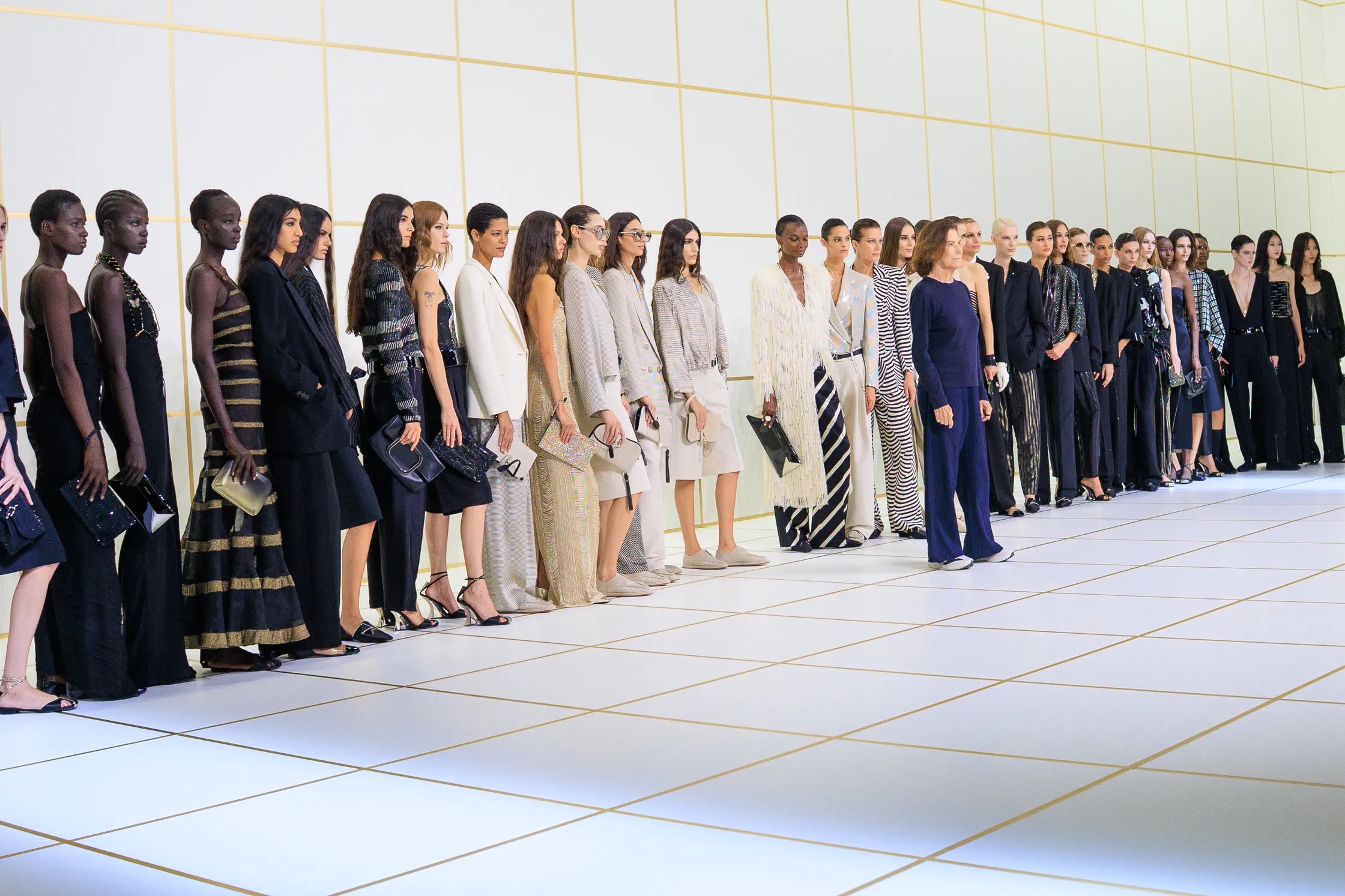 Fila de modelos alineadas en el backstage luciendo las diversas propuestas de la colección, desde trajes pantalón hasta vestidos largos de noche, fotografiadas por Acielle StyleDuMonde.