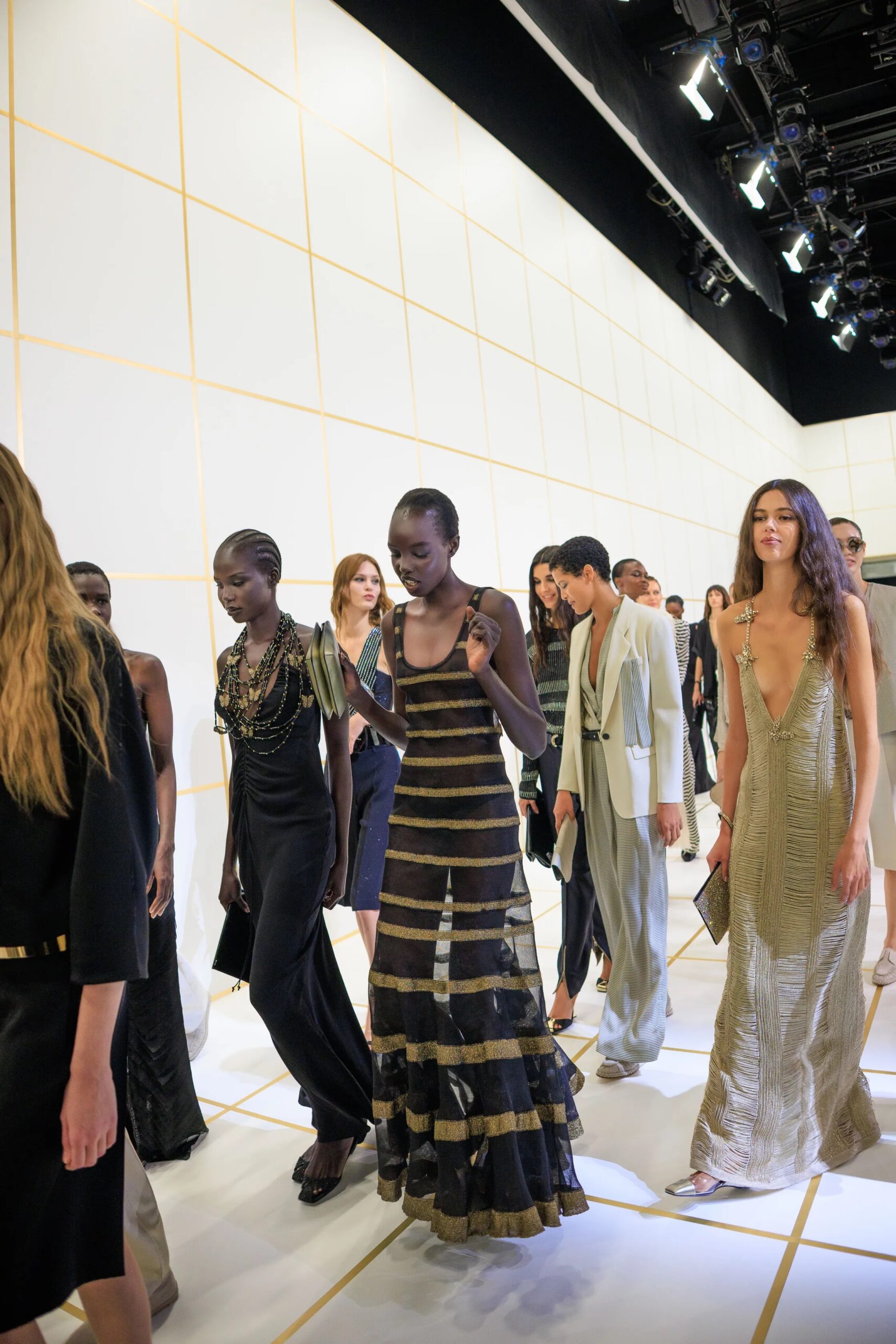 Modelos desfilando por la pasarela con vestidos largos de noche fluidos con detalles metalizados y de rayas horizontales, capturadas por Acielle StyleDuMonde.