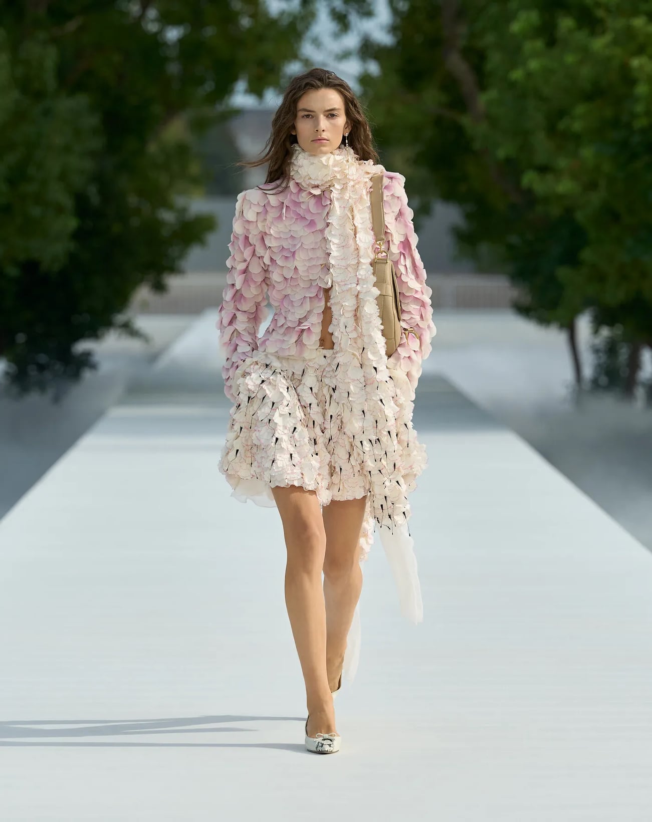 Modelo vestida de saco, bufanda y falda con pétalos floreales de Dior