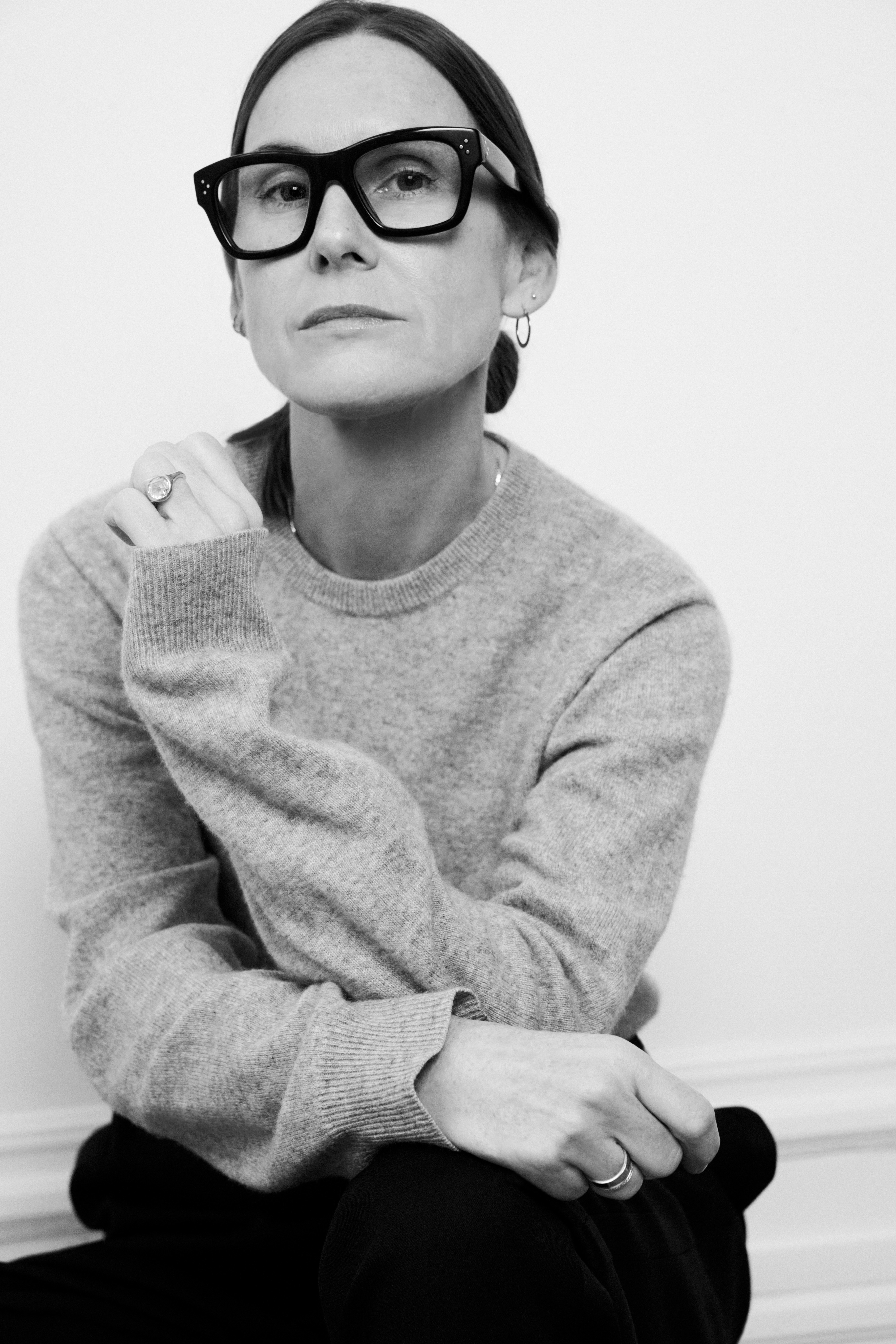 Retrato en blanco y negro de Louise Trotter con gafas de pasta negra, suéter gris de punto y una expresión serena.