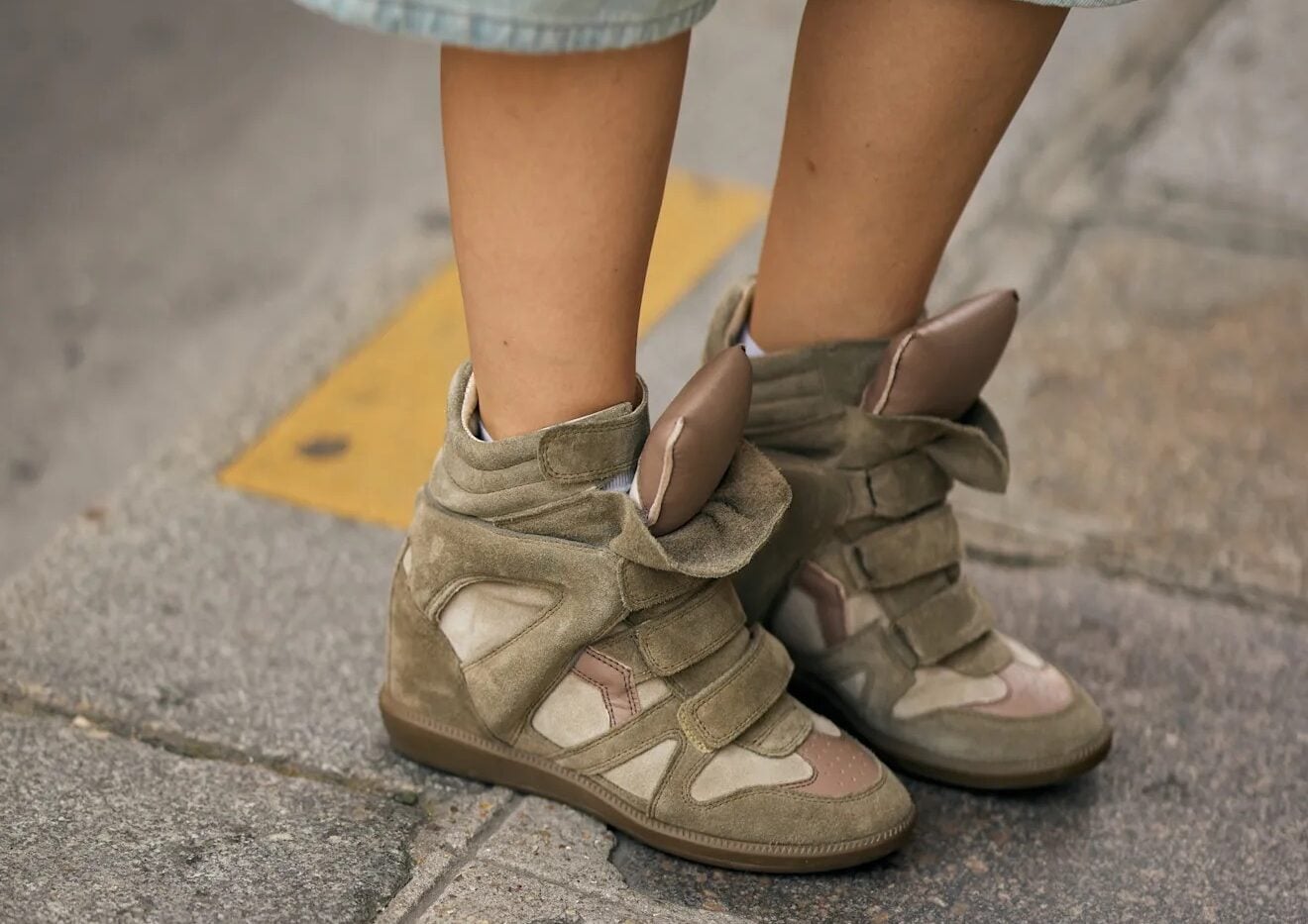 Vista de las piernas de una persona con bermudas de mezclilla clara y zapatillas altas de plataforma con cierres de velcro en tonalidades verde oliva y beige.