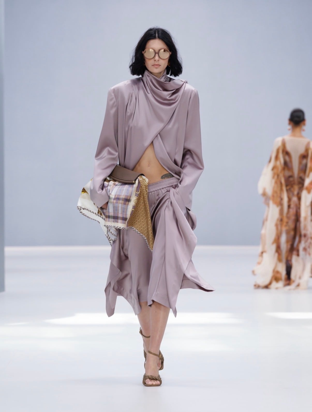 Modelo con blusa lila de seda larga semi abierta con bermudas de seda lila y lentes redondos Zimmermann