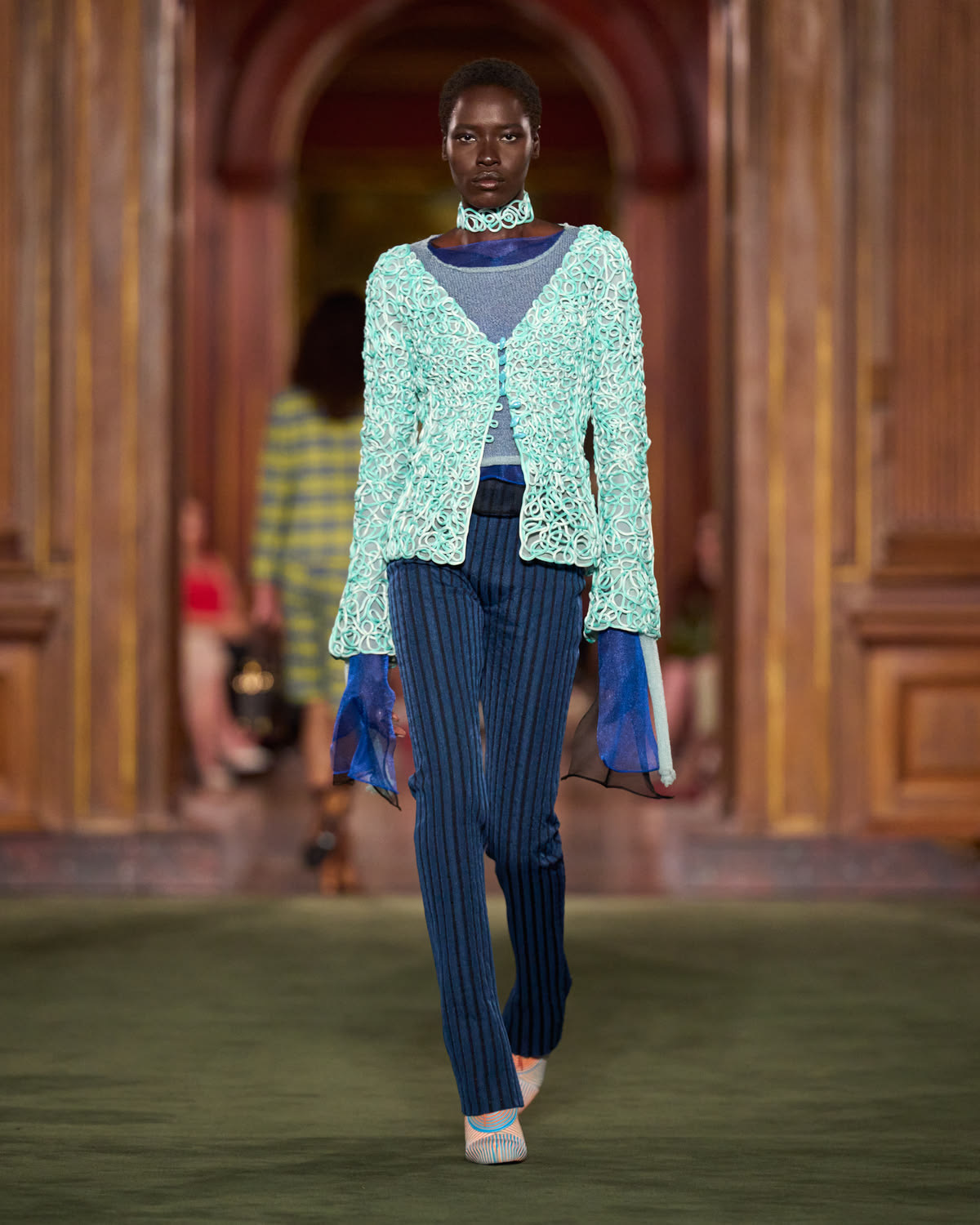 Mujer con suéter tejido blanco con turquesa y pantalones azules de rayas PFW