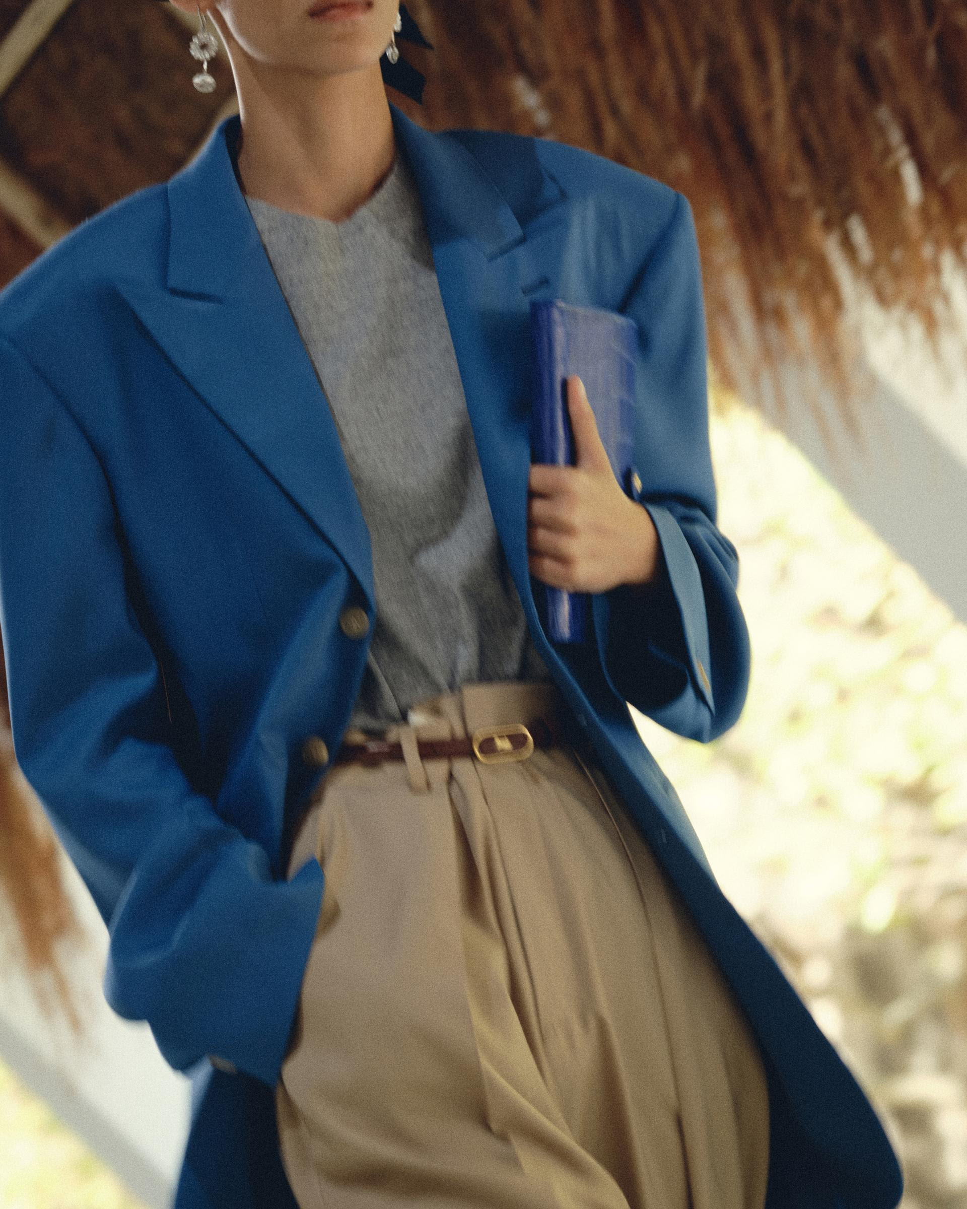 Blazer azul con hombreras, blusa gris y pantalón beige