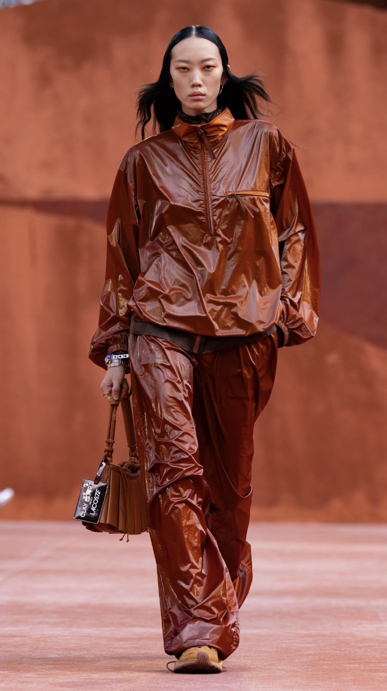 Modelo con chamarra y pants deportivos en color ladrillo desfile Lacoste