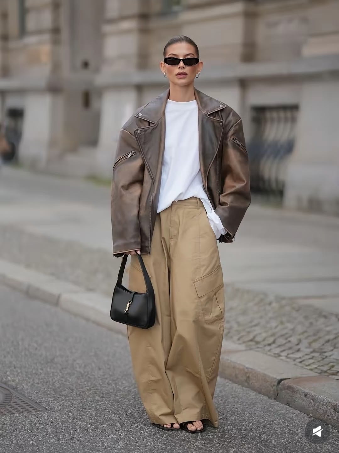 Mujer con pantalones cargo beige, blusa blanca y chamarra de piel