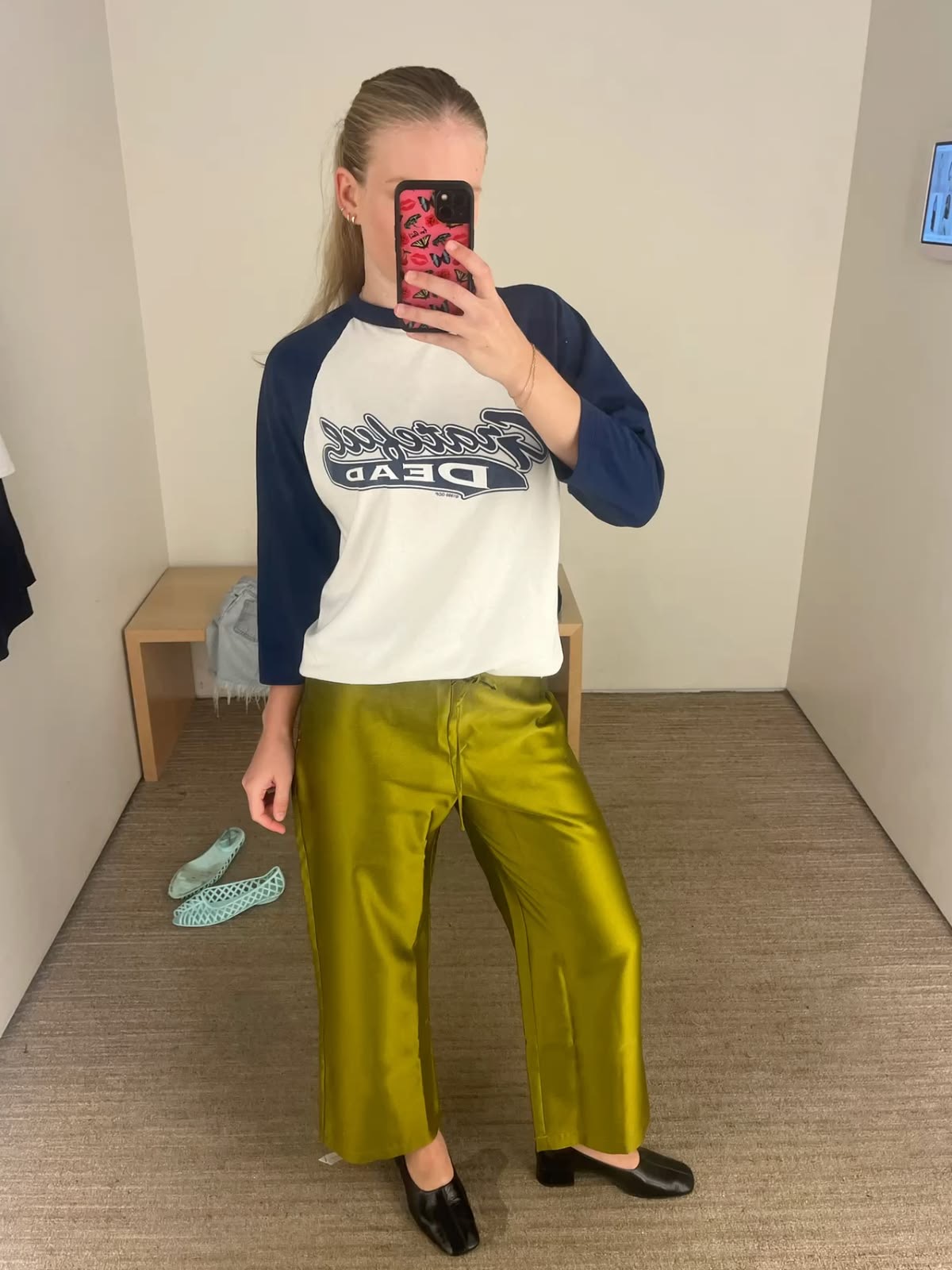 Foto frente al espejo de mujer con pantalones verdes de seda y camiseta de manga larga