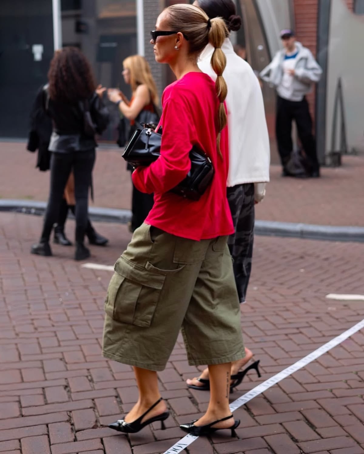 Persona caminando con pantalones capri verde y camiseta de manga larga roja
