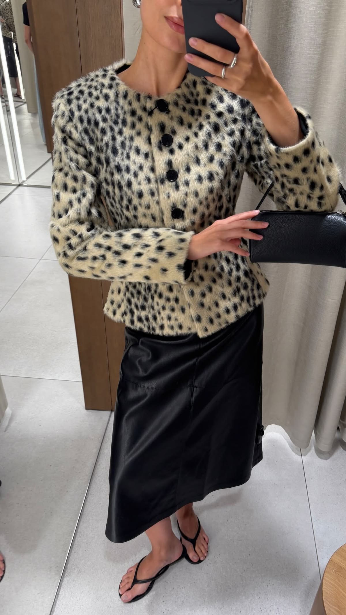 Foto de espejo con mujer en falda negra con chaqueta animal print sin cuello