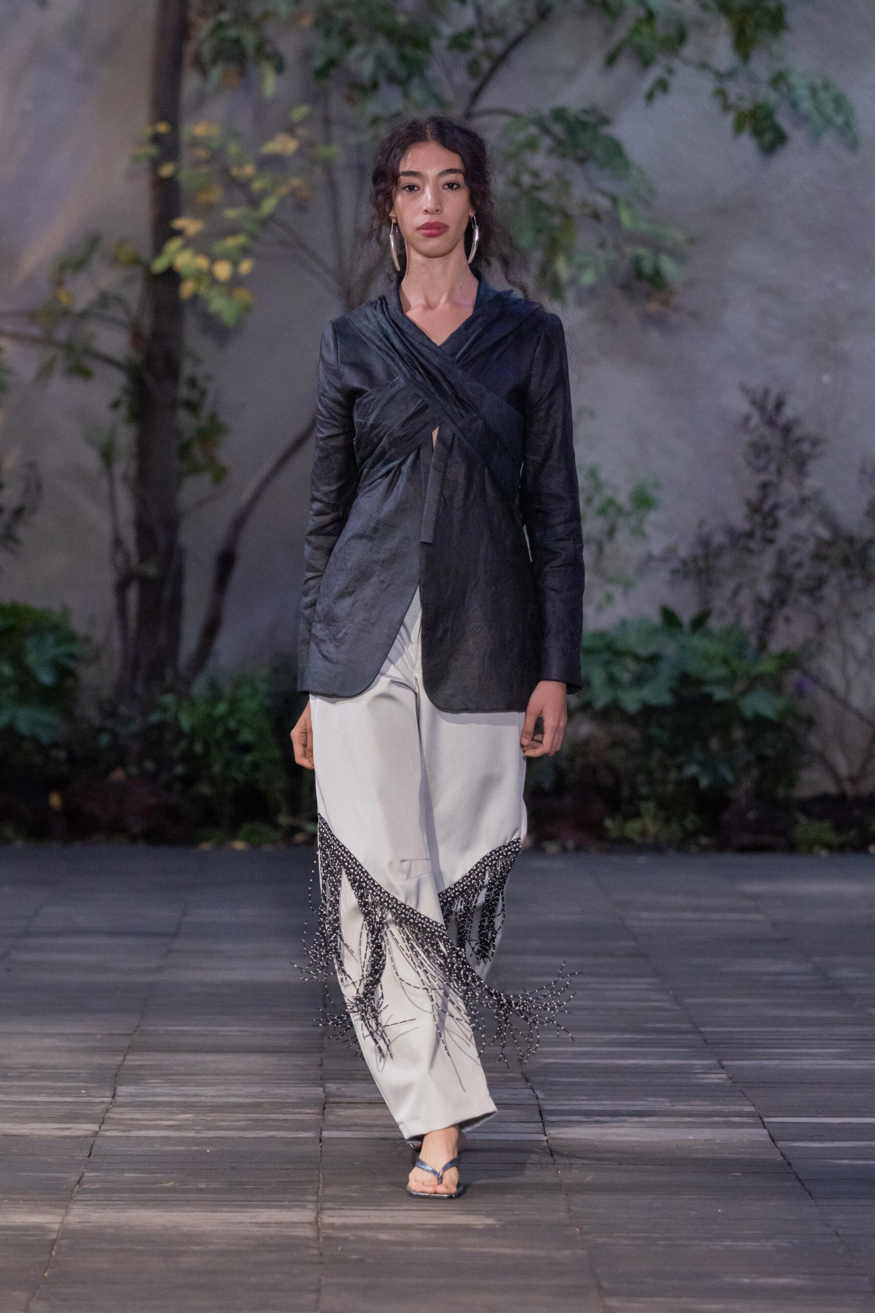 Modelo con camisa negra y pantalones blancos con chaquiras