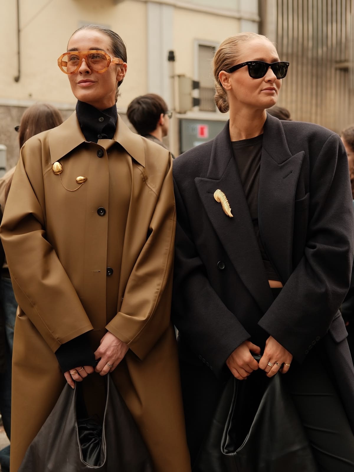 2 mujeres de lentes con un broche en sus abrigos