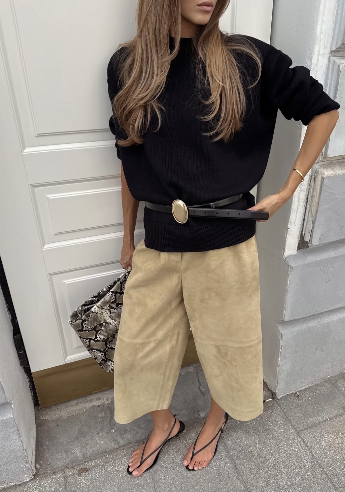 Bermudas beige suede con blusa negra y cinturón con hebilla dorada