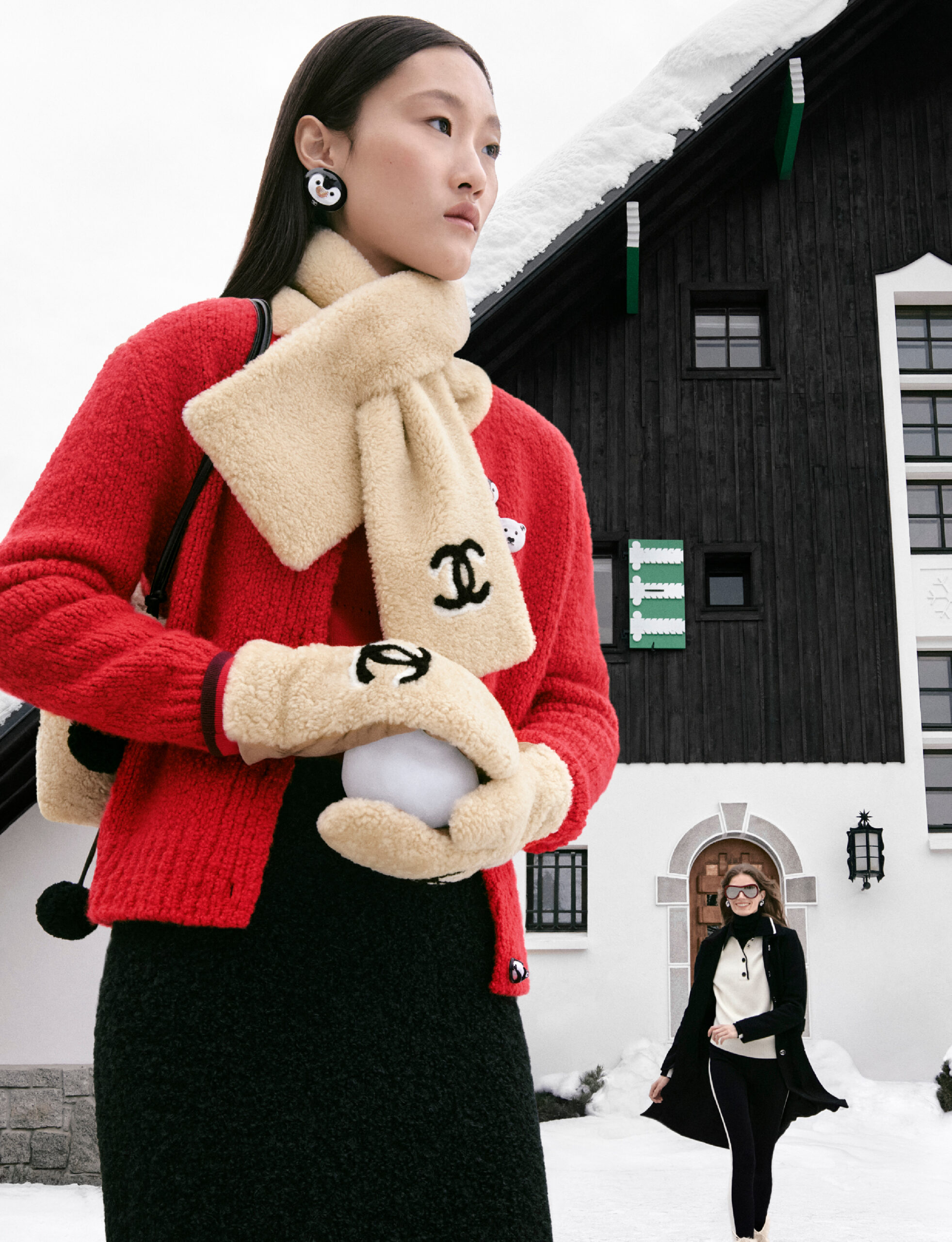 mujer con suéter rojo y guantes y bufanda beige con bola de nieva en la mano