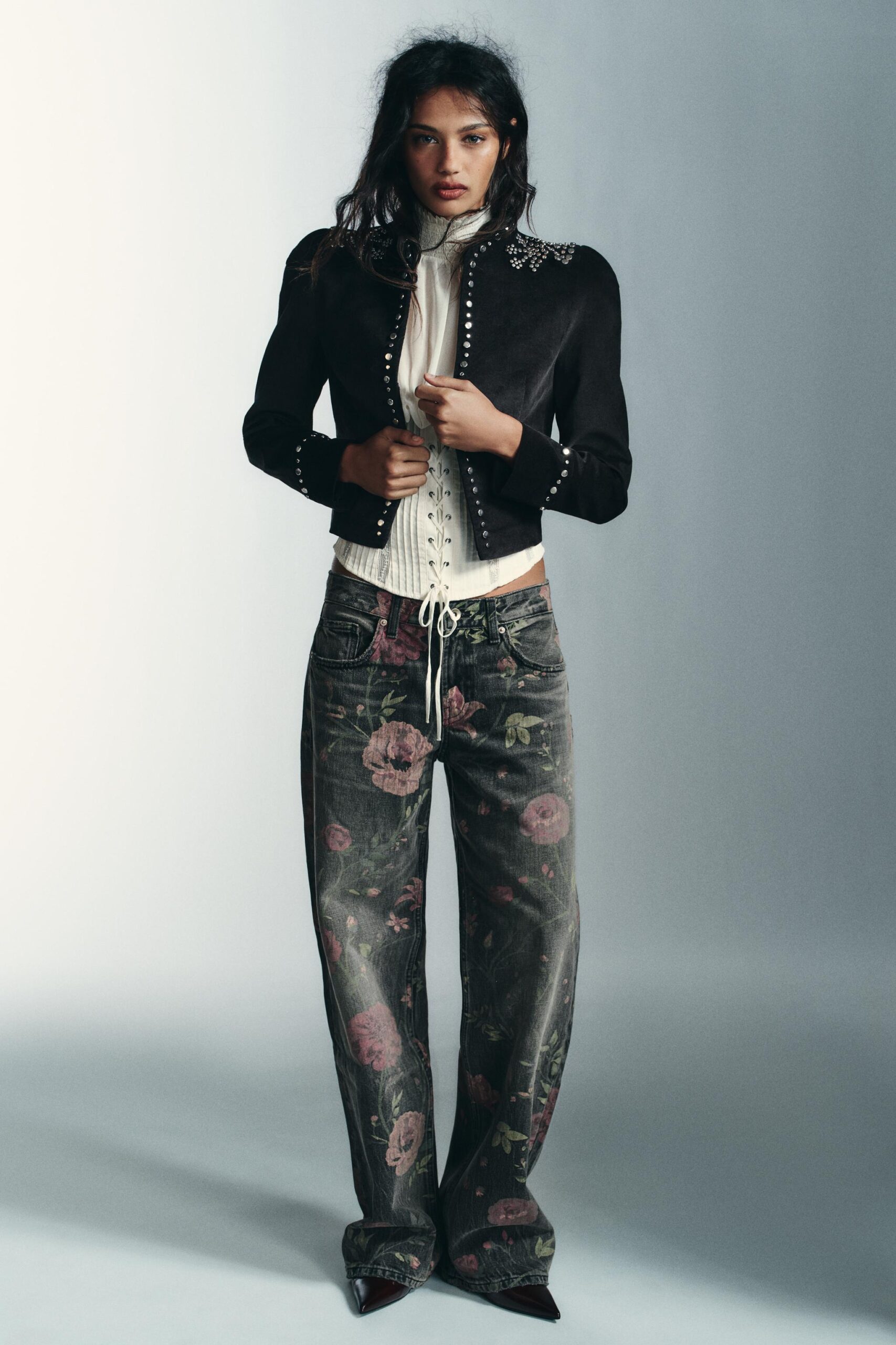modelo con jeans estampados de flores, blusa blanca y saco negro