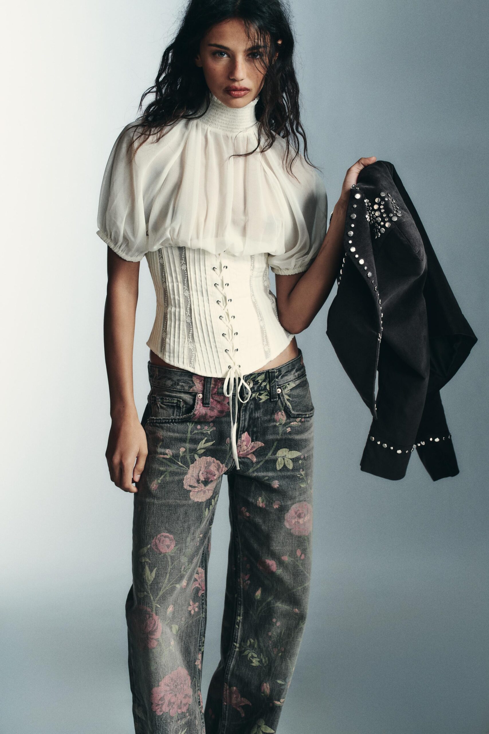 Mujer con blusa corsé jeans de flores y saco en la mano colección ZARA día de muertos 