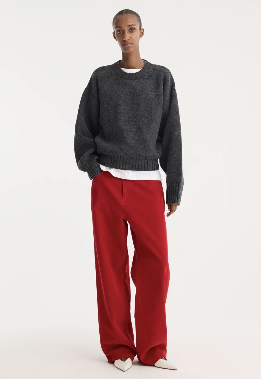 Modelo con cardigan gris y pantalones rojos